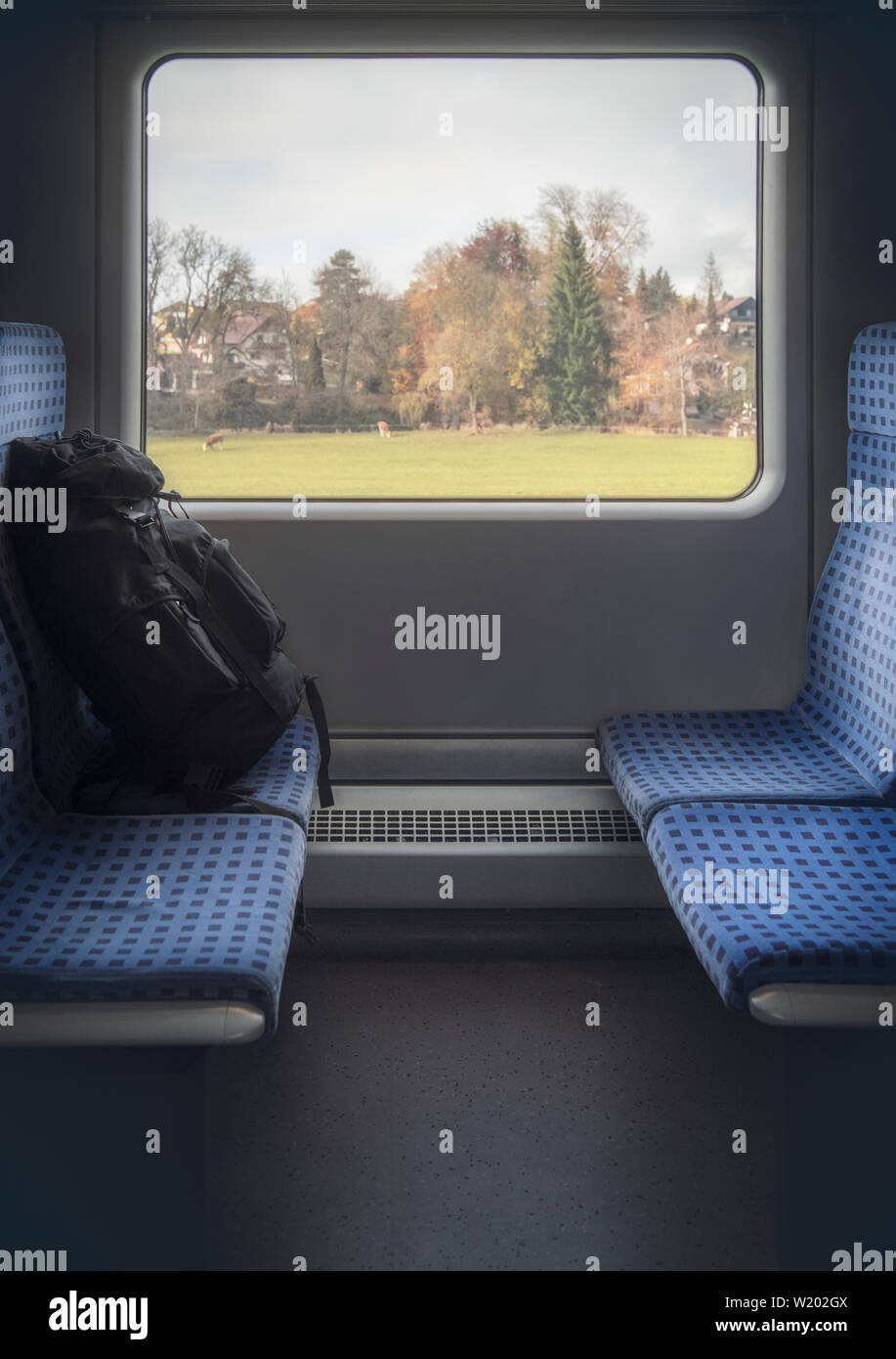Vertikale Bild der Deutschen Bahn Innenraum mit blauen Stühlen, Gepäck und einen Herbst Blick auf das Fenster. Reisen in Deutschland mit einer Regionalbahn. Stockfoto