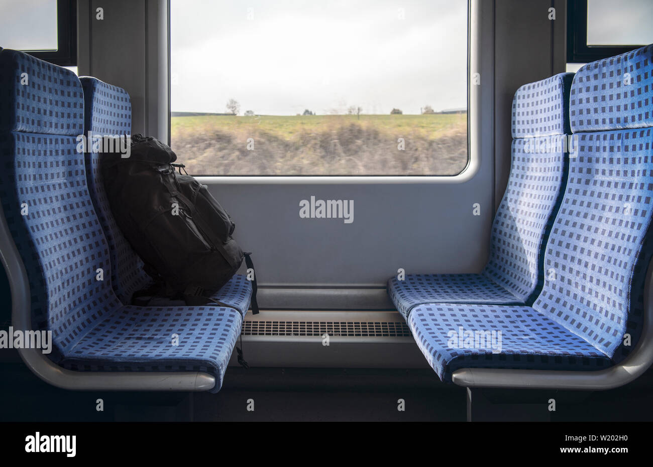 Gepäck auf dem blauen Stühlen eines Deutschen Regionalbahn und ein Fenster mit einem bewegungsbild. Reisen in Deutschland Konzept. Reisezeit. Stockfoto