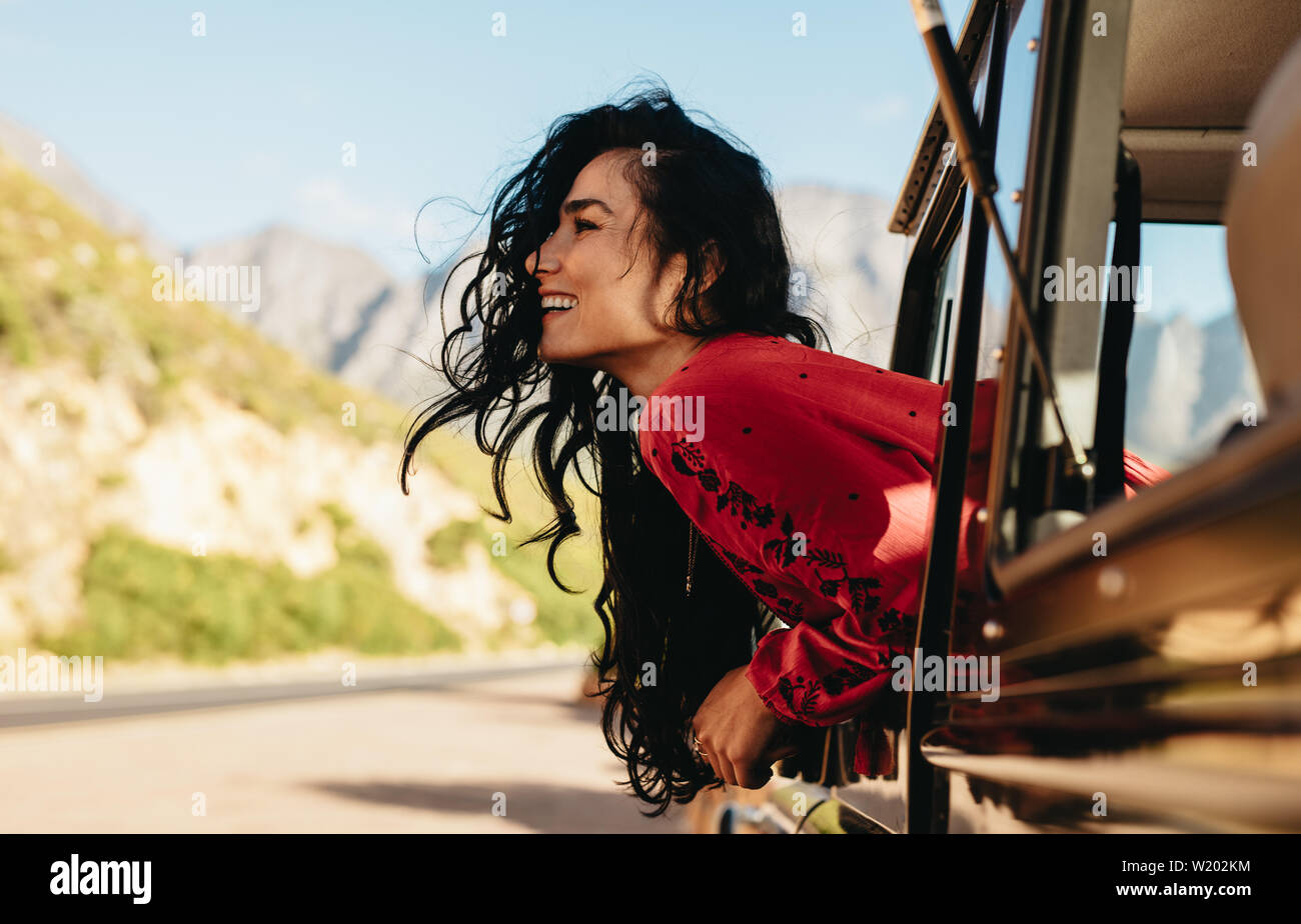Schöne kaukasische Frau suchen aus dem Auto und lächelnd auf Road Trip. Frau Spaß zu haben, während sie von einem Auto unterwegs. Stockfoto