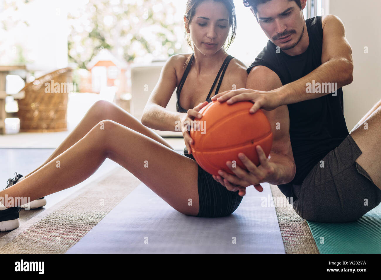 Fitness paar Übungen mit einem medizinball zu Hause. Paar zurück auf eine Yogamatte, indem Sie die Kugel zu jeder anderen Ausübung sitzen. Stockfoto