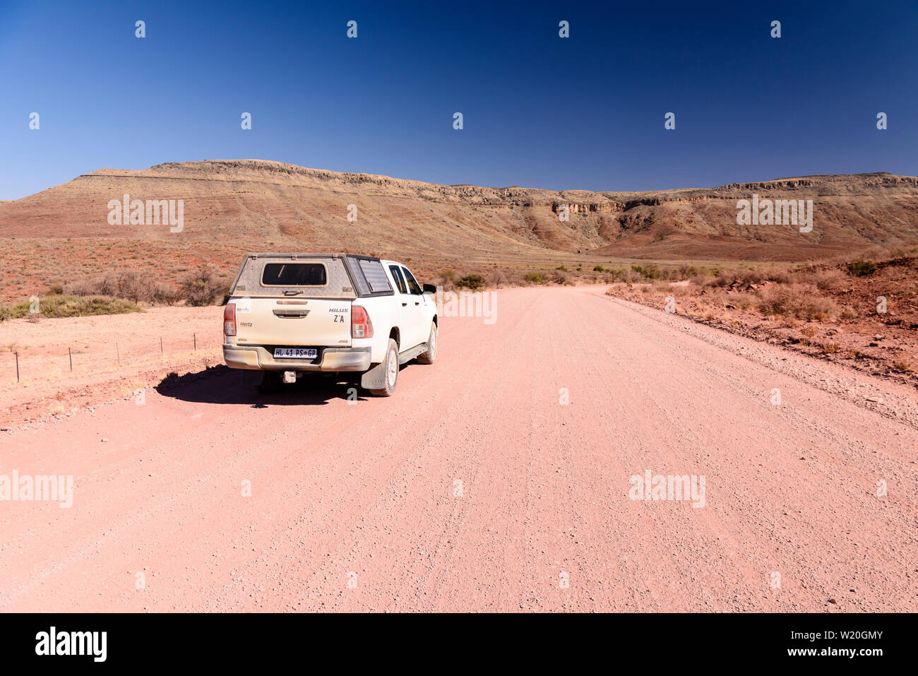 Toyota Hilux Antriebe entlang einer Schotter Piste in Richtung Berge in Zentral Namibia führenden Stockfoto