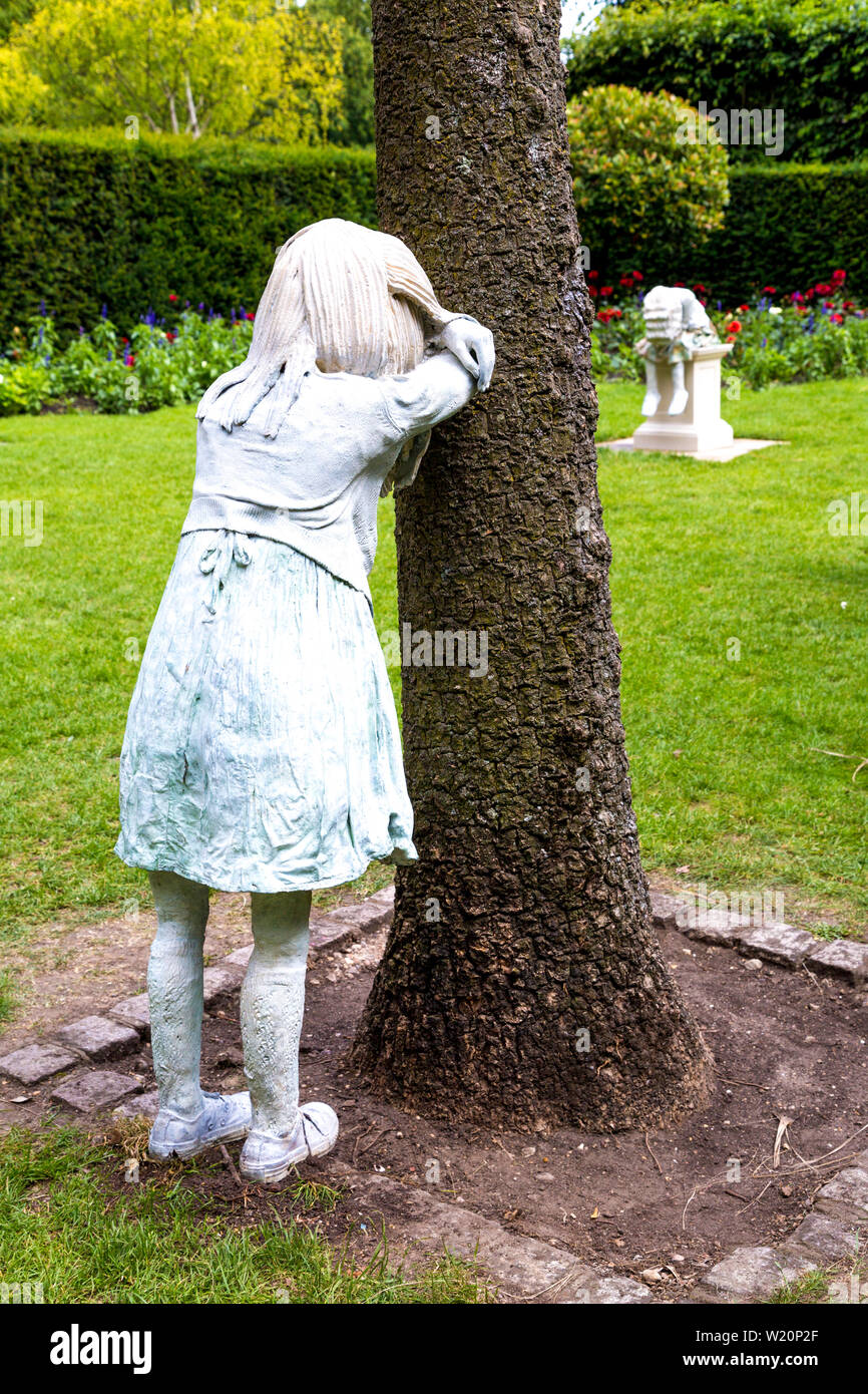 Skulpturen von Mädchen spielen verstecken und in Holland Park, Silent Howlers von Laura Ford, Teil von Kensington und Chelsea Art Wochenende 2019, London, UK suchen Stockfoto