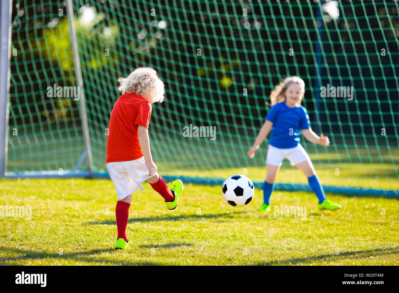 Kinder spielen Fußball im freien Feld. Kinder ein Tor beim Fußball-Spiel. Mädchen und Jungen treten Ball. Mit Kind im Team Jersey und Stollen. Schule Stockfoto
