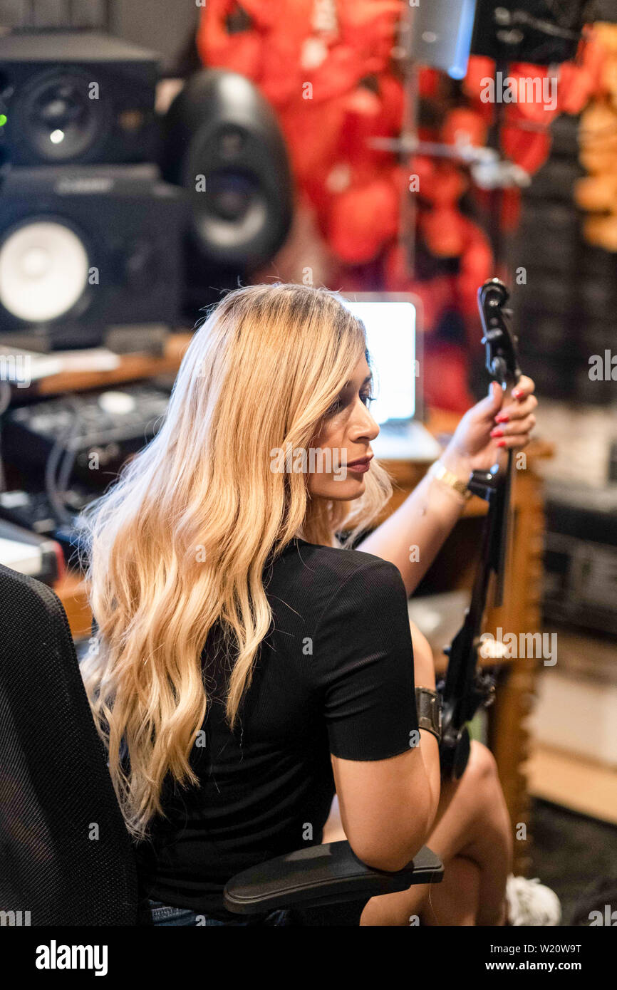 Musik Recording Session in der modernen Musik Studio. Die Geräte einschließlich der Violine, Tastaturen, Lautsprecher und Tastaturen. Blonde Frau Musiker. Stockfoto