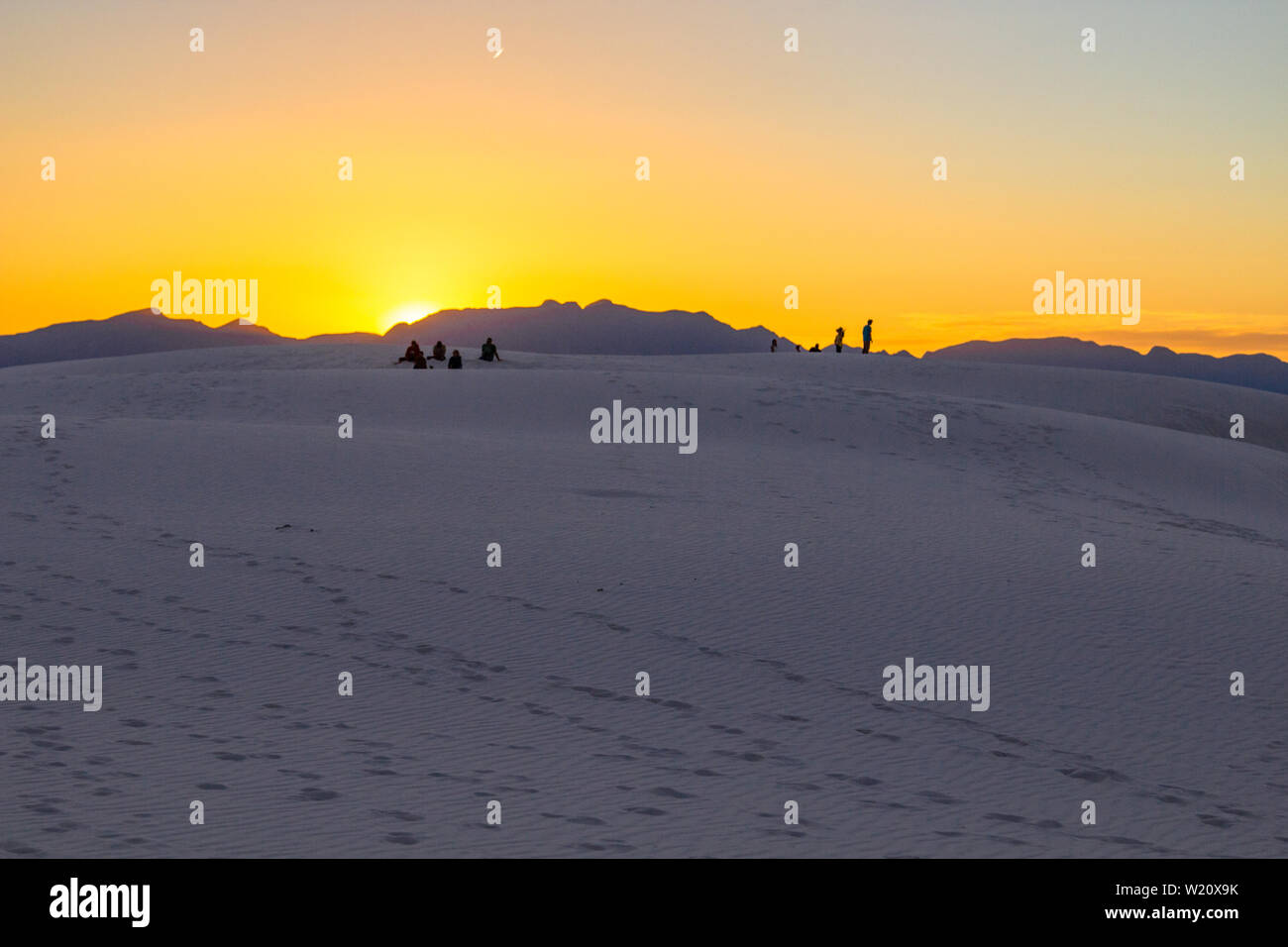 Touristen beobachten EINEN Sonnenuntergang in der Wüste. Touristen stehen auf einer Sanddüne und bewundern den Sonnenuntergang am White Sands in New Mexico. Stockfoto