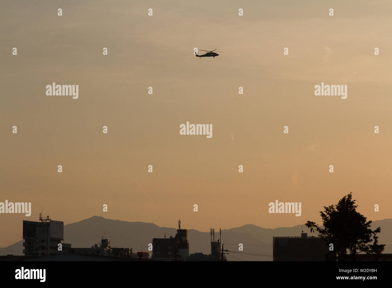 Ein Sikorsky SH-60 Seahawk Hubschrauber in Silhouette, der bei Sonnenuntergang von der Naval Air Facility Atsugi, Luftwaffenstützpunkt, Kanagawa, Japan, fliegt. Stockfoto