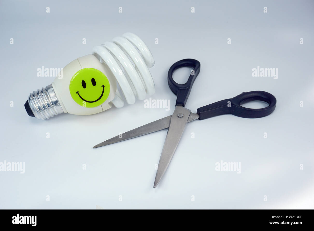 Sparen Sie Geld bei der Senkung von Kosten wallet Schere Energiesparlampe Strom smiley auf weißem Hintergrund glücklich Stockfoto