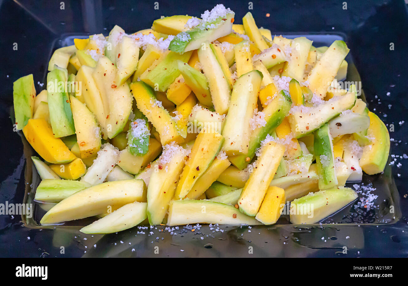Mango in kleine Stücke schneiden, mit Salz bestreuen, Pfeffer und Zucker. Stockfoto
