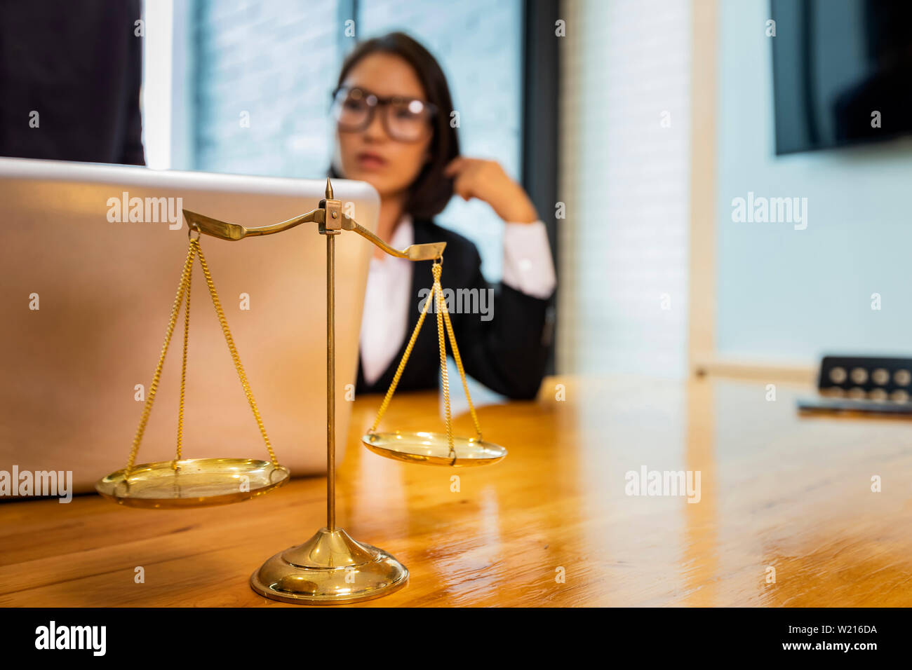 Waagen und Rechtsanwalt, der an einem Notebook arbeitet. Rechtsanwalt Büro Beratung und Gerechtigkeit Konzept. Stockfoto