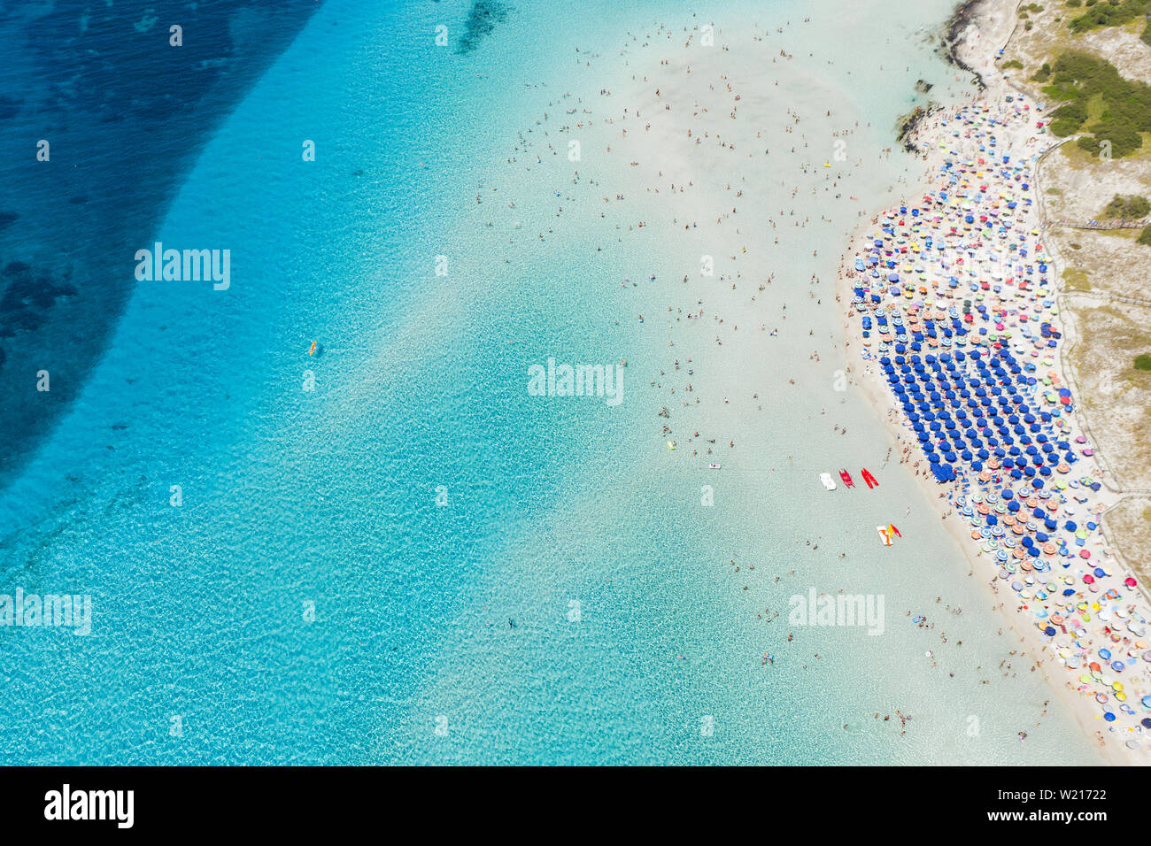 Beeindruckende Luftaufnahme der Spiaggia della Pelosa (Pelosa Strand) voll von bunten Sonnenschirmen und Menschen sonnenbaden. Stockfoto