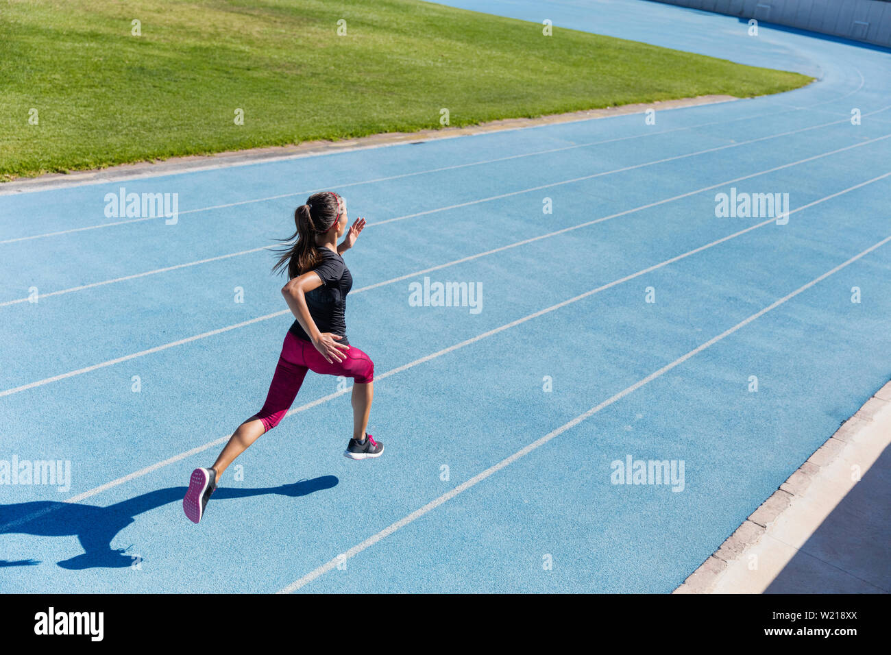 Läufer sprintete in Richtung Erfolg auf Run weg Leichtathletikbahn. Zielerreichung Konzept. Weibliche Athlet Sprinter einen schnellen Sprint für Wettbewerb auf Blue Lane an einer im Bereich Stadion. Stockfoto