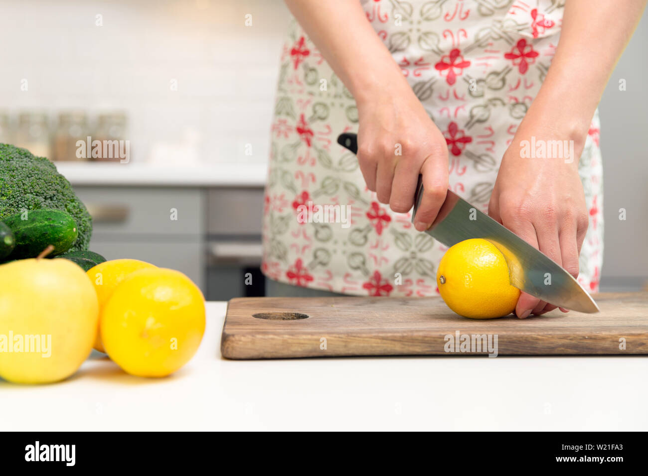 Frau wird von Hand mit einem Messer schneiden Zitrone auf Holzbrett. Grüne smoothie Zubereitung Stockfoto