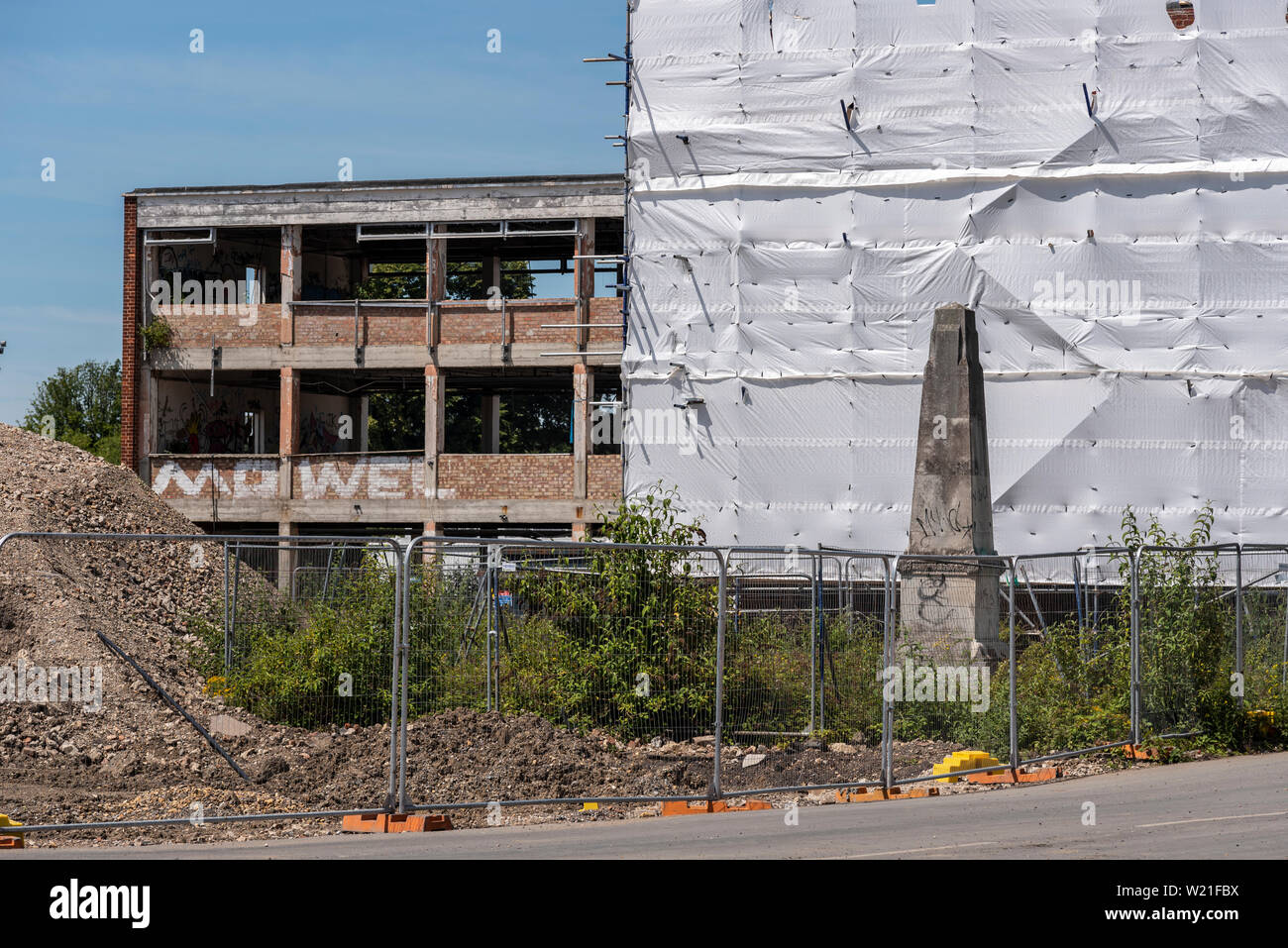 Kriegerdenkmal unter Fechten und Abbruchbaustelle, ICI Brantham, Manningtree, Suffolk, Großbritannien. Brantham Industrial Estate. Denkmalgeschütztes Gebäude Stockfoto