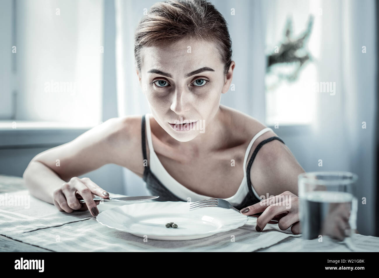 Schlecht fühlen. Ernsthafte Brünette mit Messer und Gabel beim Gehen Frühstück zu haben Stockfoto