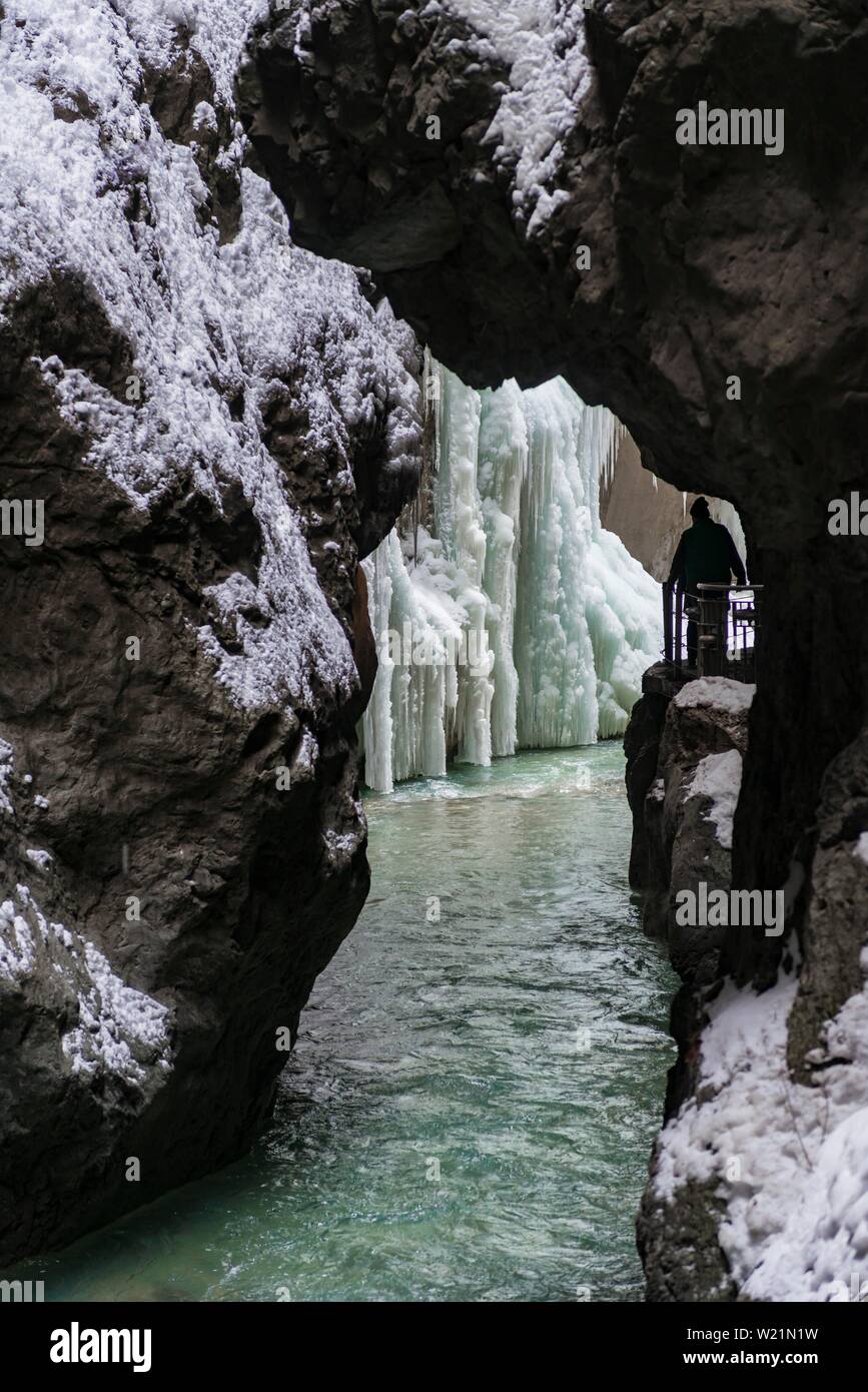 Junge Frau in die eisige Partnachklamm mit Eiszapfen und Schnee im Winter, in der Nähe von Garmisch-Partenkirchen, Oberbayern, Bayern, Deutschland Stockfoto