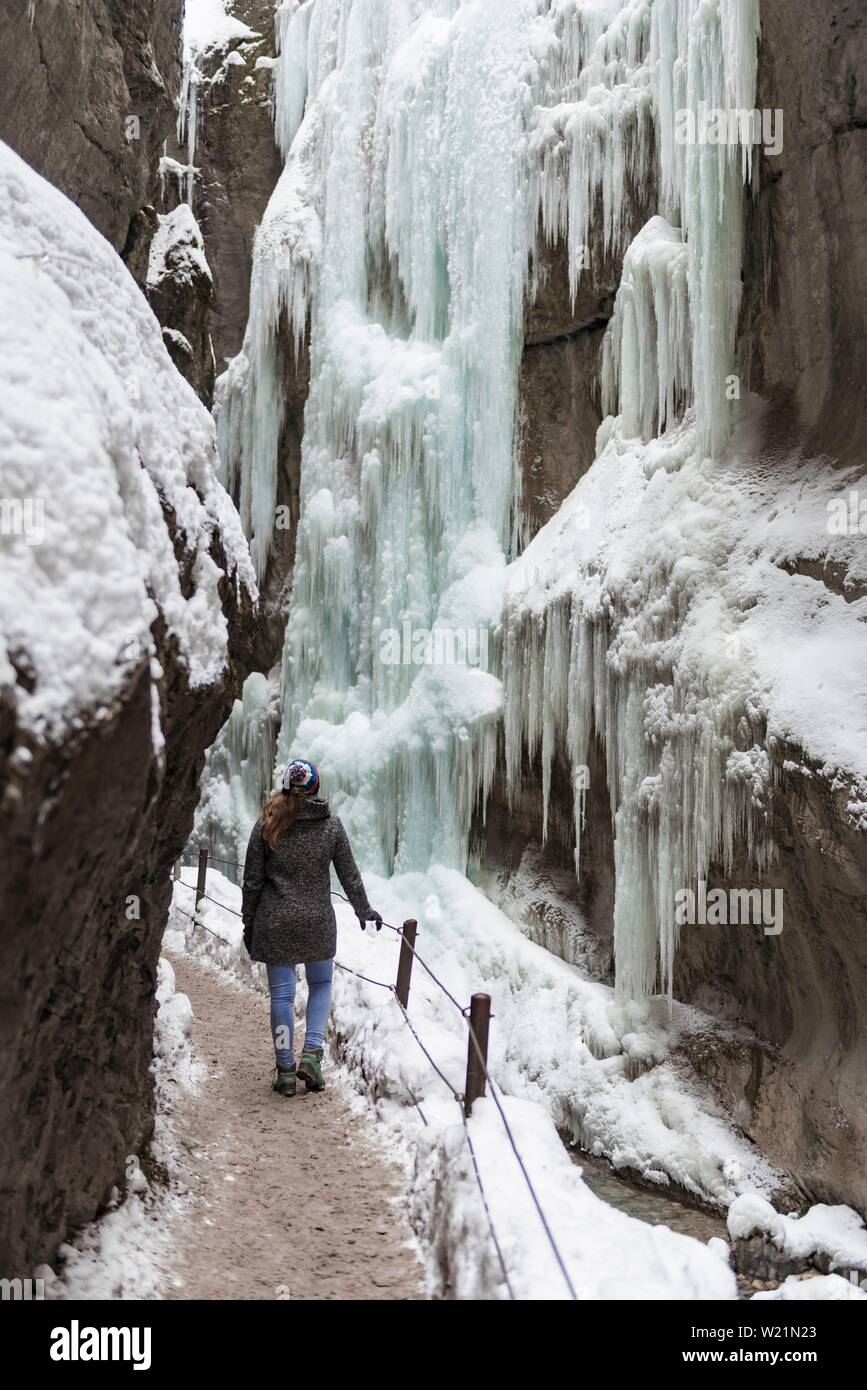 Junge Frau in die eisige Partnachklamm mit Eiszapfen und Schnee im Winter, in der Nähe von Garmisch-Partenkirchen, Oberbayern, Bayern, Deutschland Stockfoto