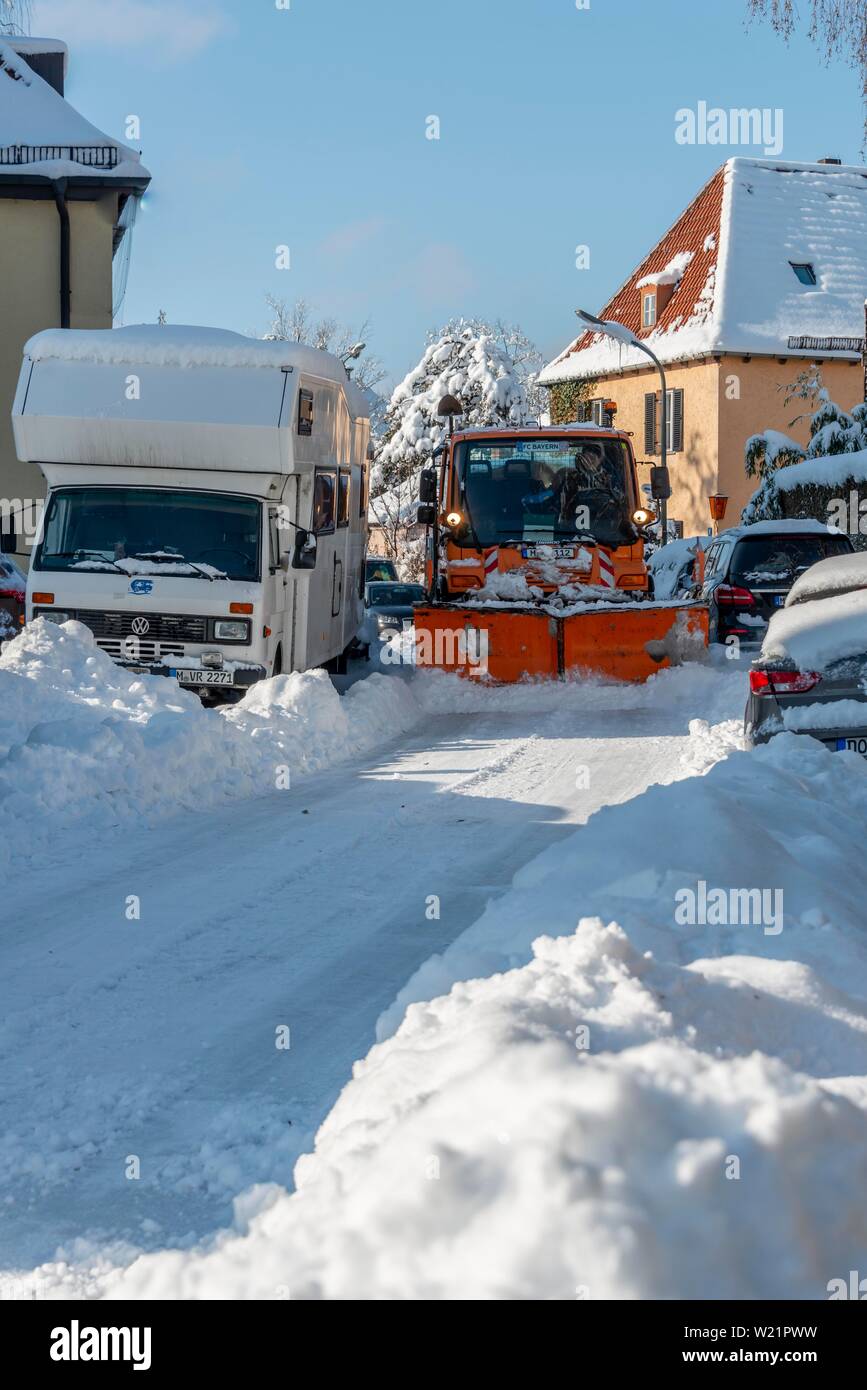 Schneepflug fährt durch enge Strasse mit Schnee geparkten Autos, München, Oberbayern, Bayern, Deutschland Stockfoto
