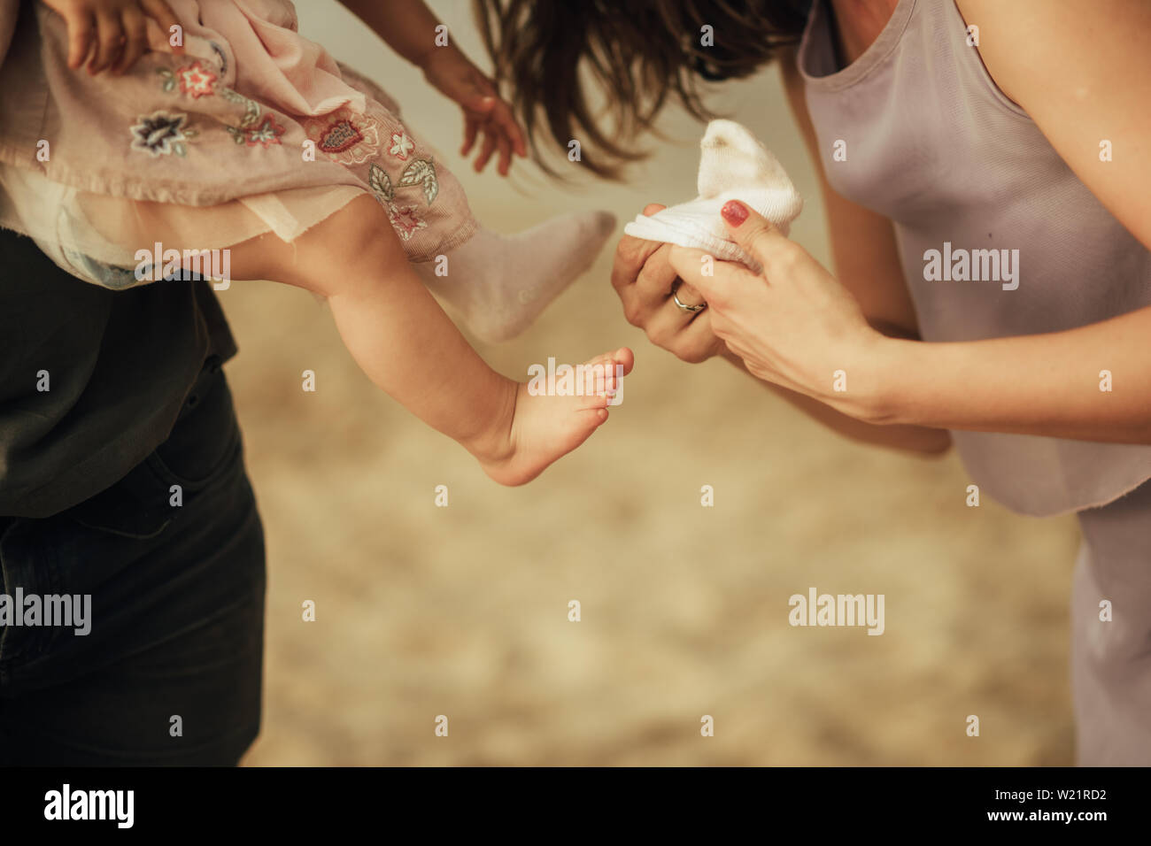 Mutter setzt eine Socke auf dem Fuß ihrer kleinen Tochter. Nahaufnahme. Stockfoto