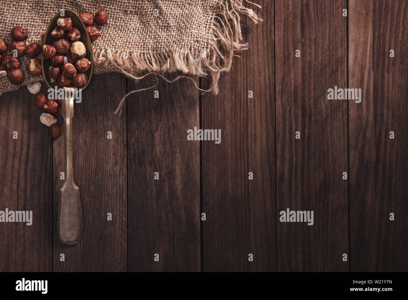 Haselnüsse auf einem alten Löffel und Zusammensetzung aus altem Holz und Material. Ansicht von oben und leeren Raum auf der rechten Seite für Ihren Text Stockfoto