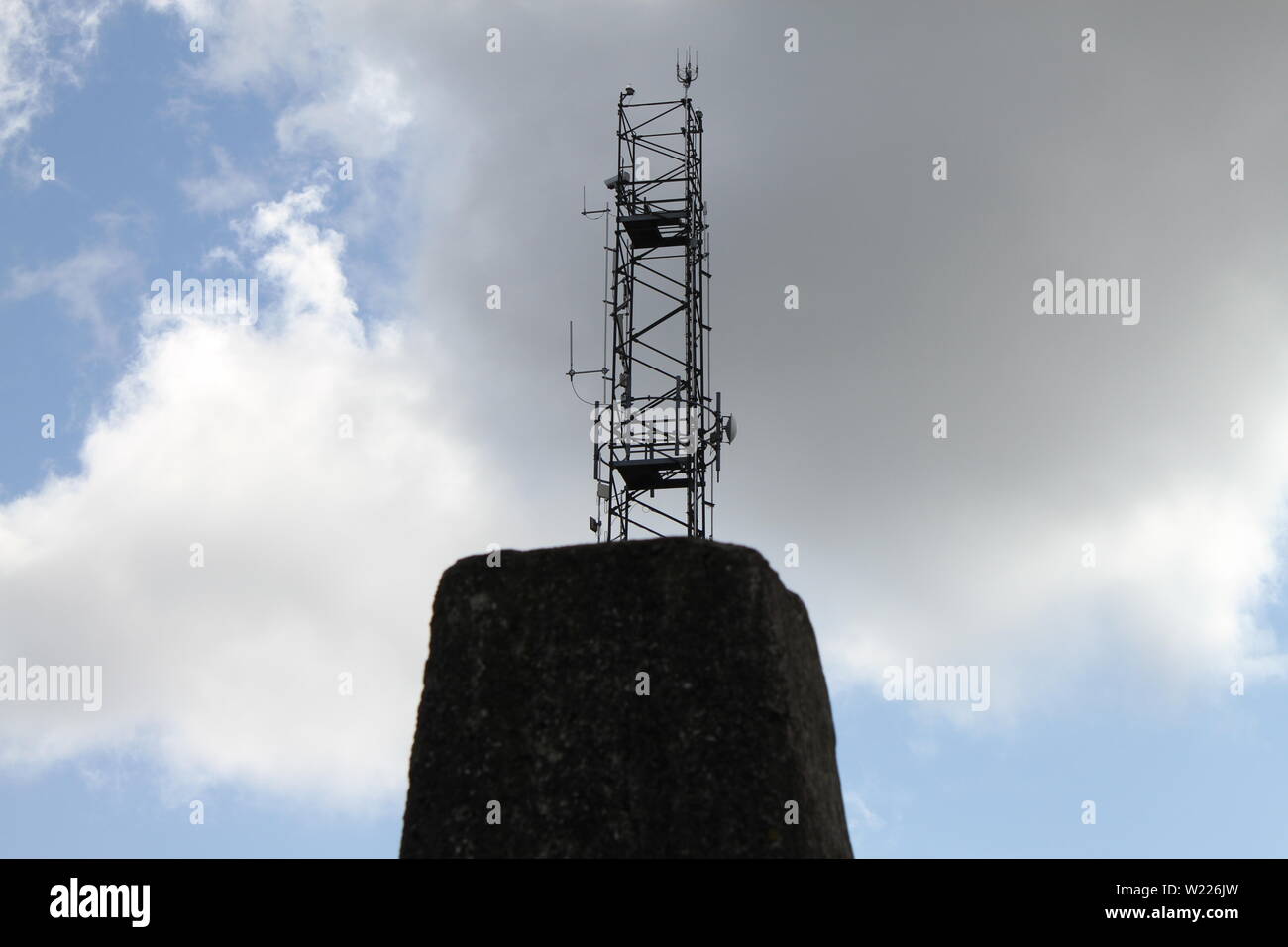 Ein Getriebe Turm hinter der trig-Säule oben Divis Berg in Nordirland, Großbritannien gesehen. Stockfoto