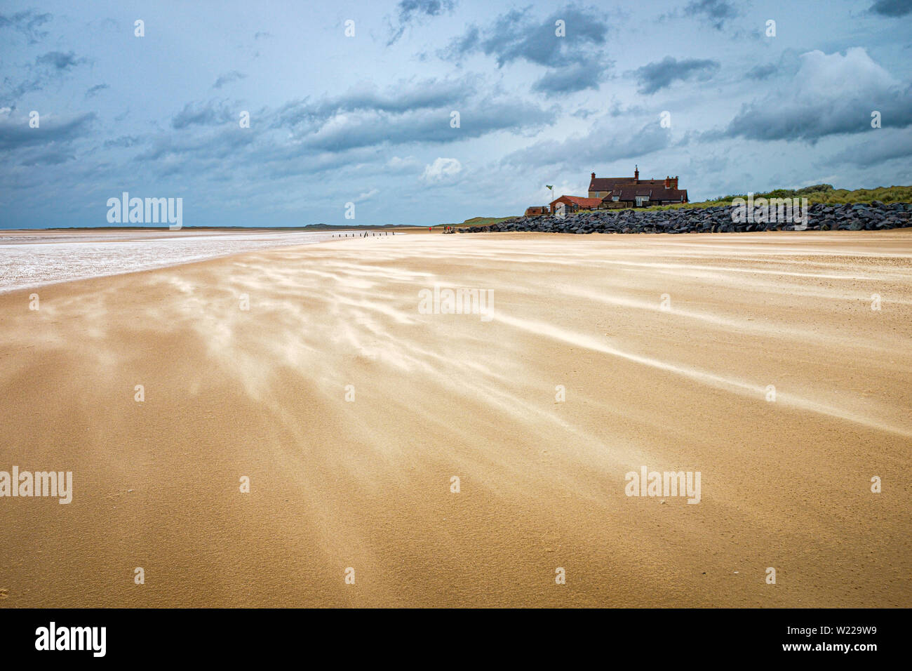 Starke Winde treiben Sand über den Strand. Stockfoto