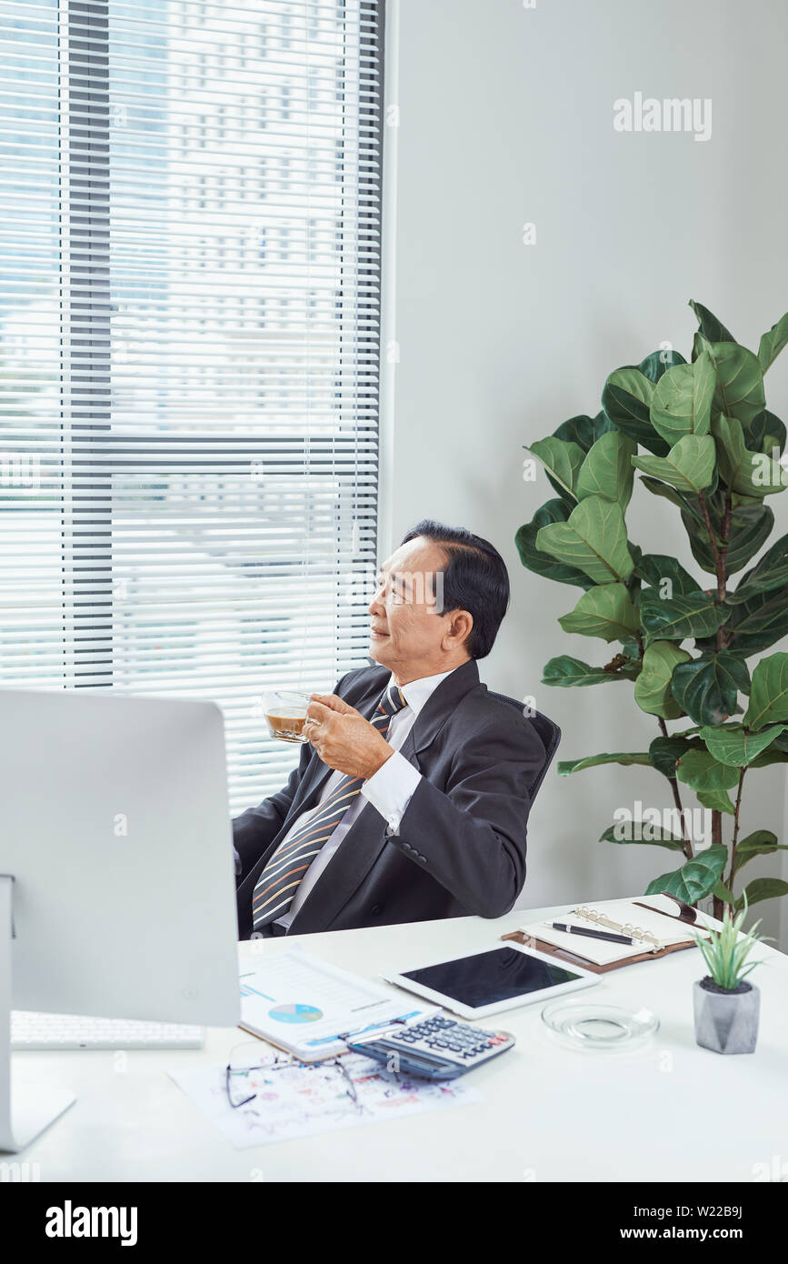 Senior Geschäftsmann entspannend an seinem Schreibtisch im Büro Stockfoto