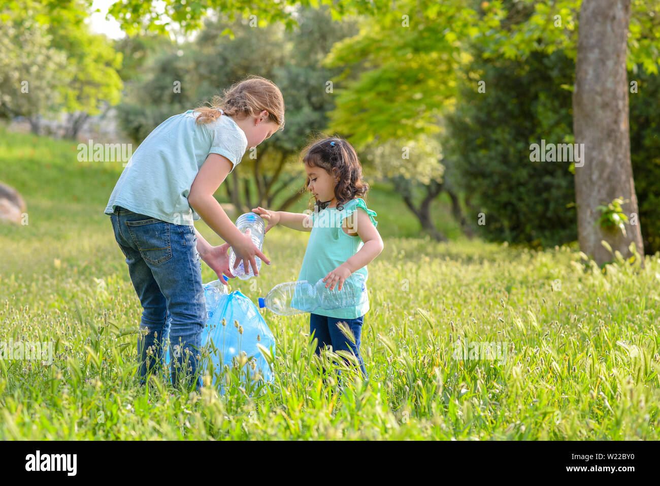 Kunststoff Verschmutzung an Land. Kinder Kommissionierung Plastikflasche aus Gras in verschmutzten Park. Stockfoto