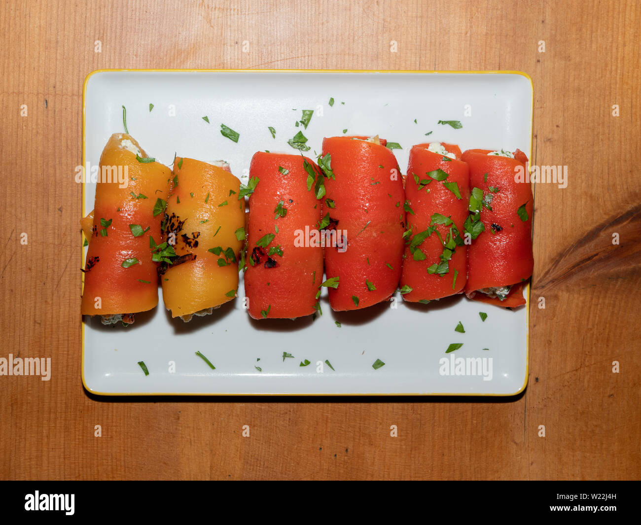 Türkische Vorspeise - Roter Pfeffer Brötchen gefüllt mit Feta und Muttern auf einem weißen rechteckigen Platte auf einem Holz Tisch - kirmizi Koz Biber Sarmasi Stockfoto