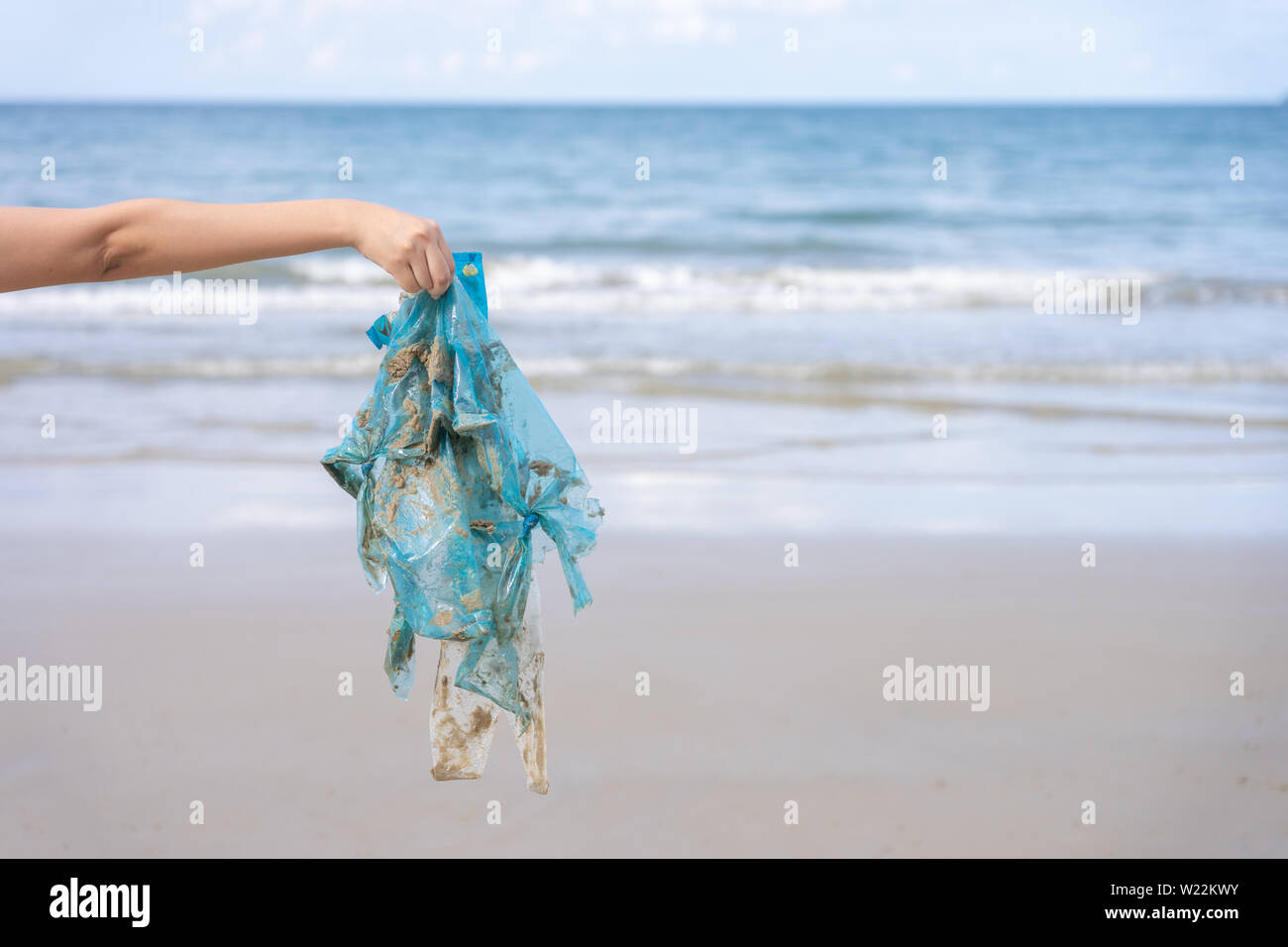 Woman's Hand herauf verwendet Plastikbeutel auf Sand Strand, Reinigung Seaside Beach. Umweltverschmutzung, ökologische Problem und Meeresverschmutzung con Stockfoto