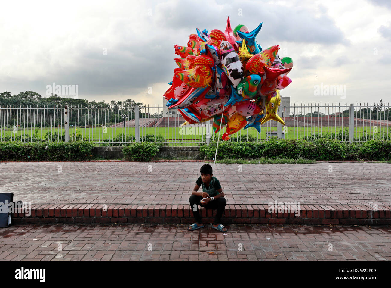 Dhaka, Bangladesch - Juli 05, 2019: Masud, kaum 13 verkauft Ballons an Manik Mia Avenue in Dhaka. Der Junge sagte, er erwirbt BDT BDT 50 10 für jeden Verkauf. Ein Stockfoto