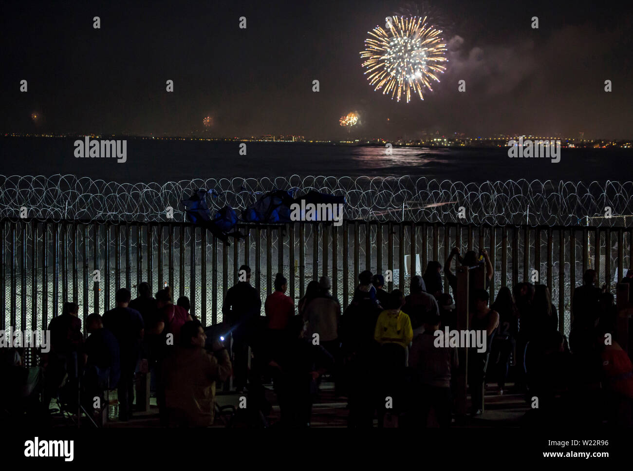 Tijuana, Mexiko. 04. Juli, 2019. Zahlreiche Menschen haben sich die Feuerwerke Leuchten hinter dem Zaun auf der mexikanischen Seite der Grenze Mauer auf US Independence Day. Menschen versammelt, um am Strand des mexikanischen Tijuana die Feiern auf der anderen Seite der Grenze zu beobachten. Credit: Omar Martinez/dpa/Alamy leben Nachrichten Stockfoto