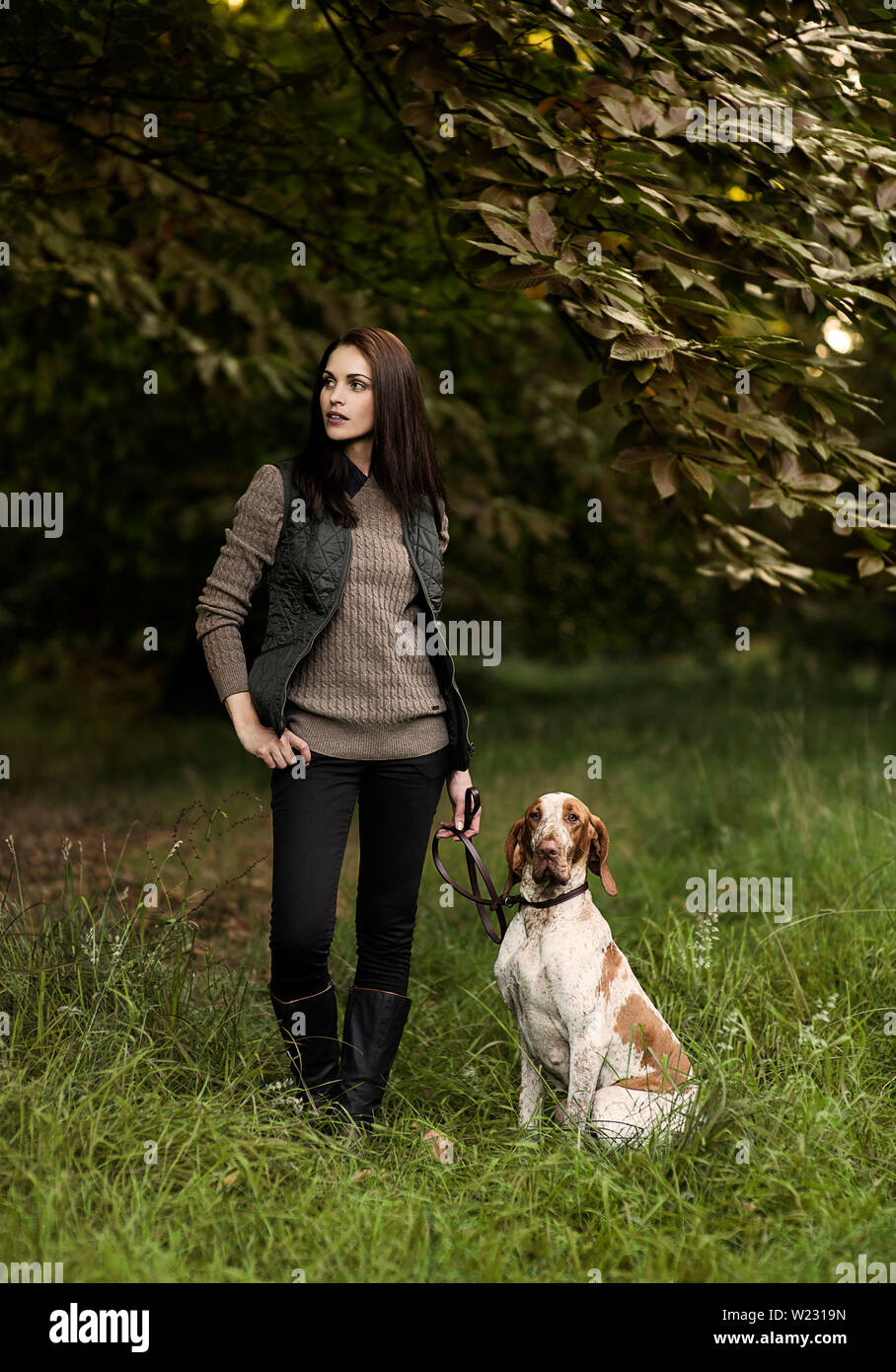Herbst Mode. Schöne 30s Frau im Land Mode/Freizeitmode in Wäldern wandern ihre Bracco Italiano Hund. Model Release zur Verfügung. Stockfoto