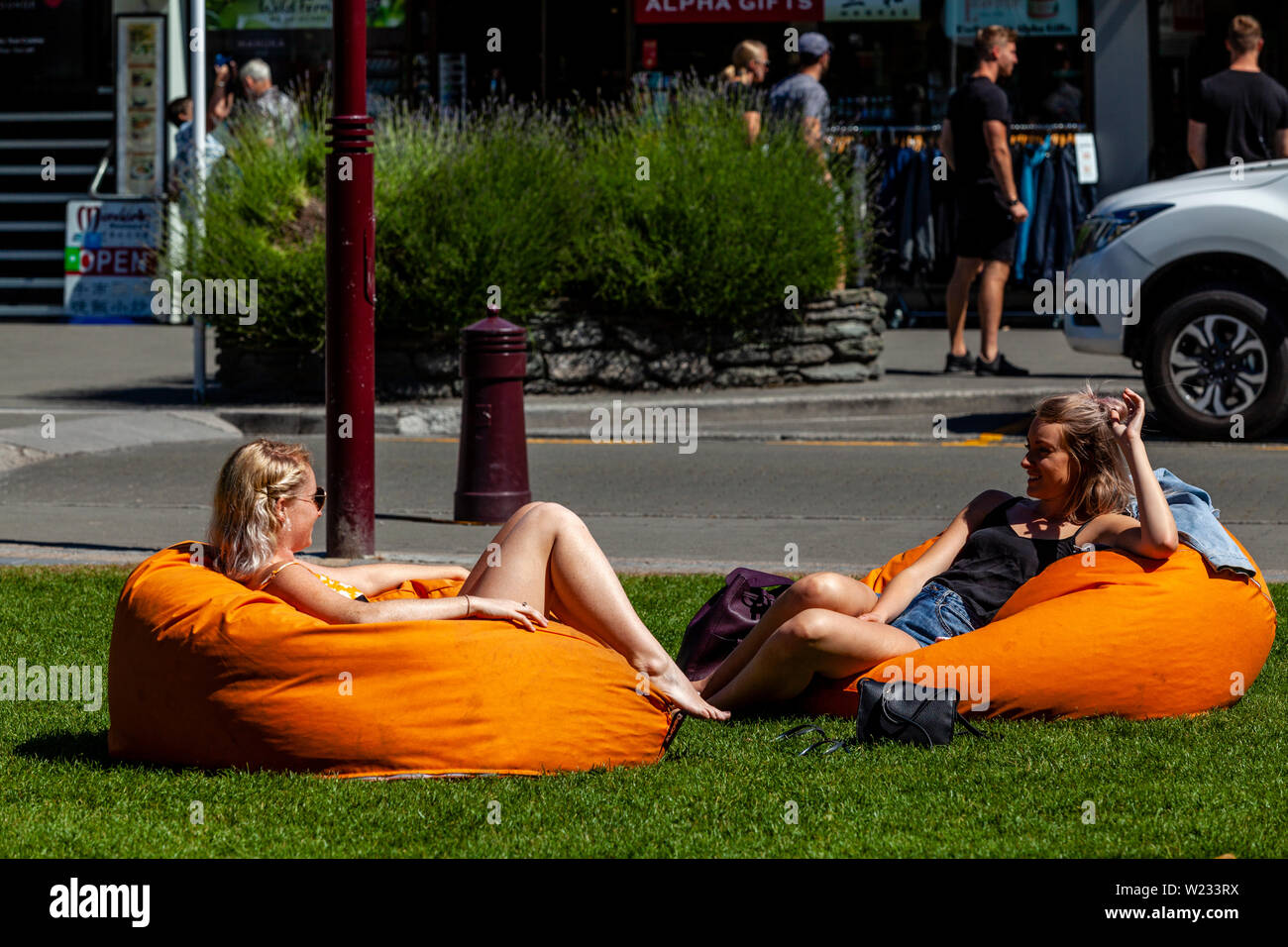 Zwei junge Frauen sitzen auf Kissen in der Innenstadt Park, Queenstown, Otago, Südinsel, Neuseeland Stockfoto