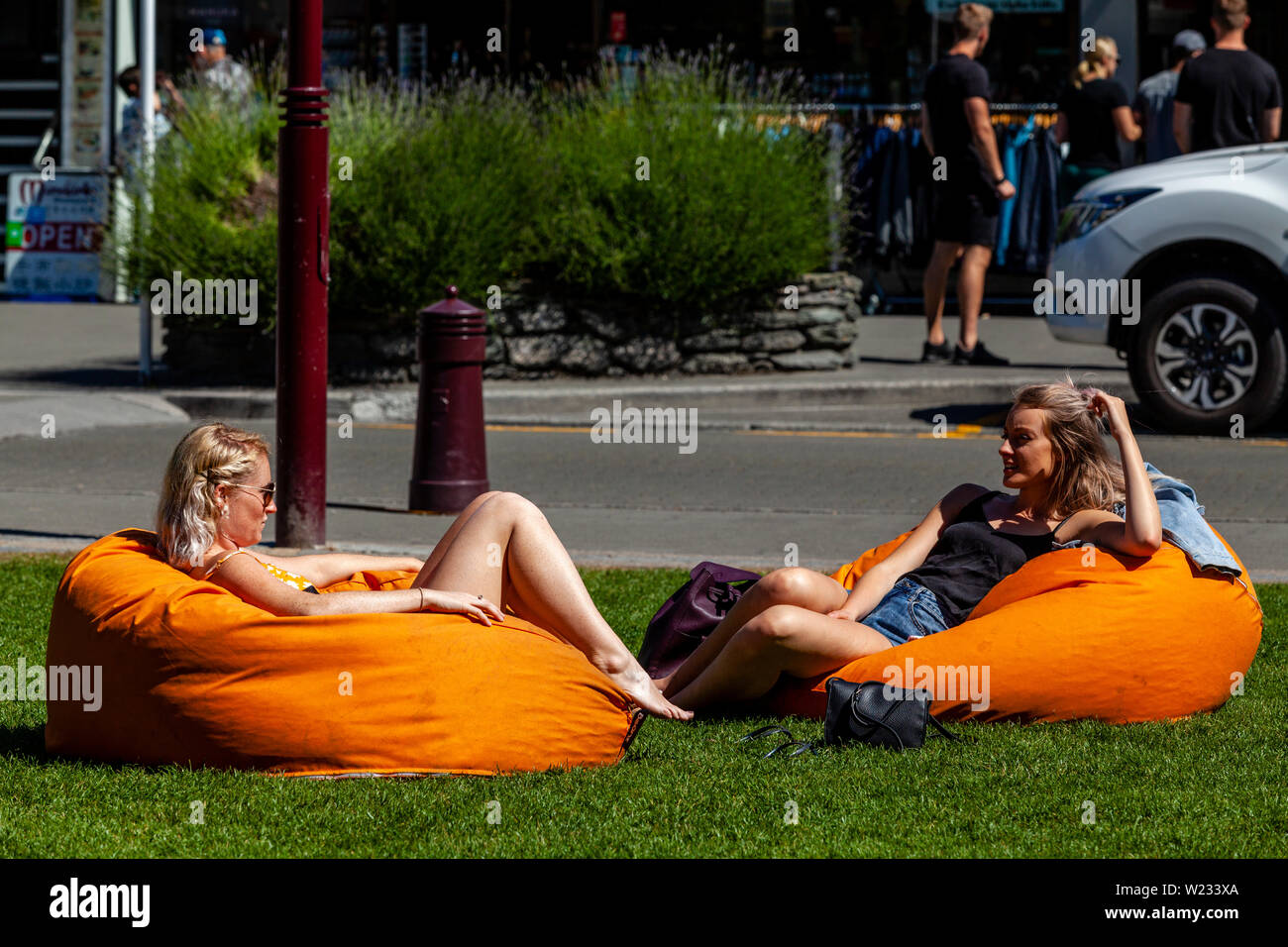 Zwei junge Frauen sitzen auf Kissen in der Innenstadt Park, Queenstown, Otago, Südinsel, Neuseeland Stockfoto