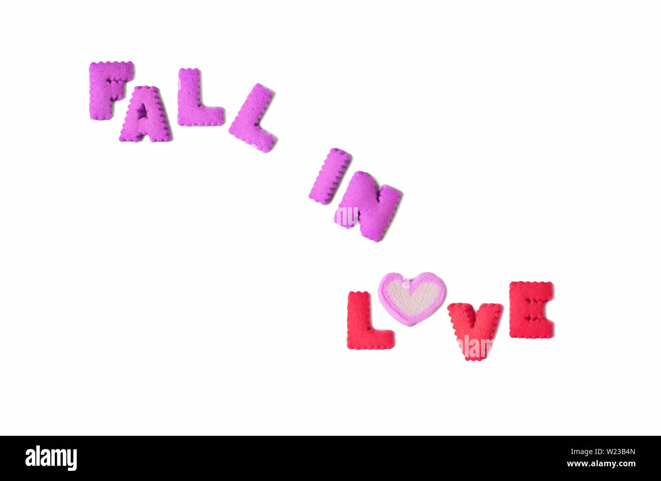 Das Wort verlieben in lila und rosa Alphabet geformte Gebäck und eine herzförmige Marshmallow candy auf weißem Hintergrund geschrieben Stockfoto