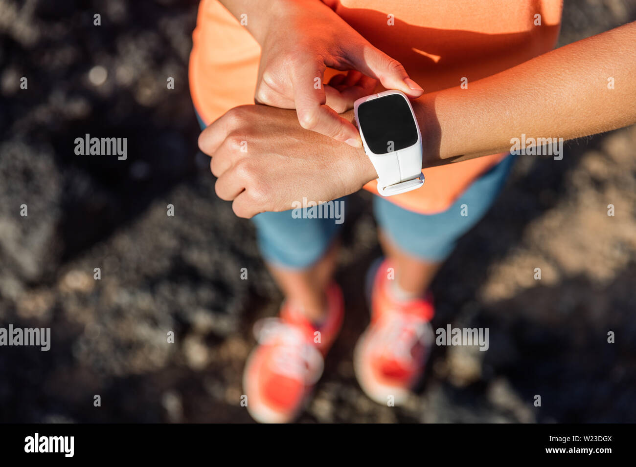 Trail Runner Athlet mit Ihrem smart Watch App fitness Fortschritt oder Herzfrequenz während Run cardio Workout zu überwachen. Frau Training im Freien auf Felsen. Nahaufnahme von Tech Gear. Stockfoto