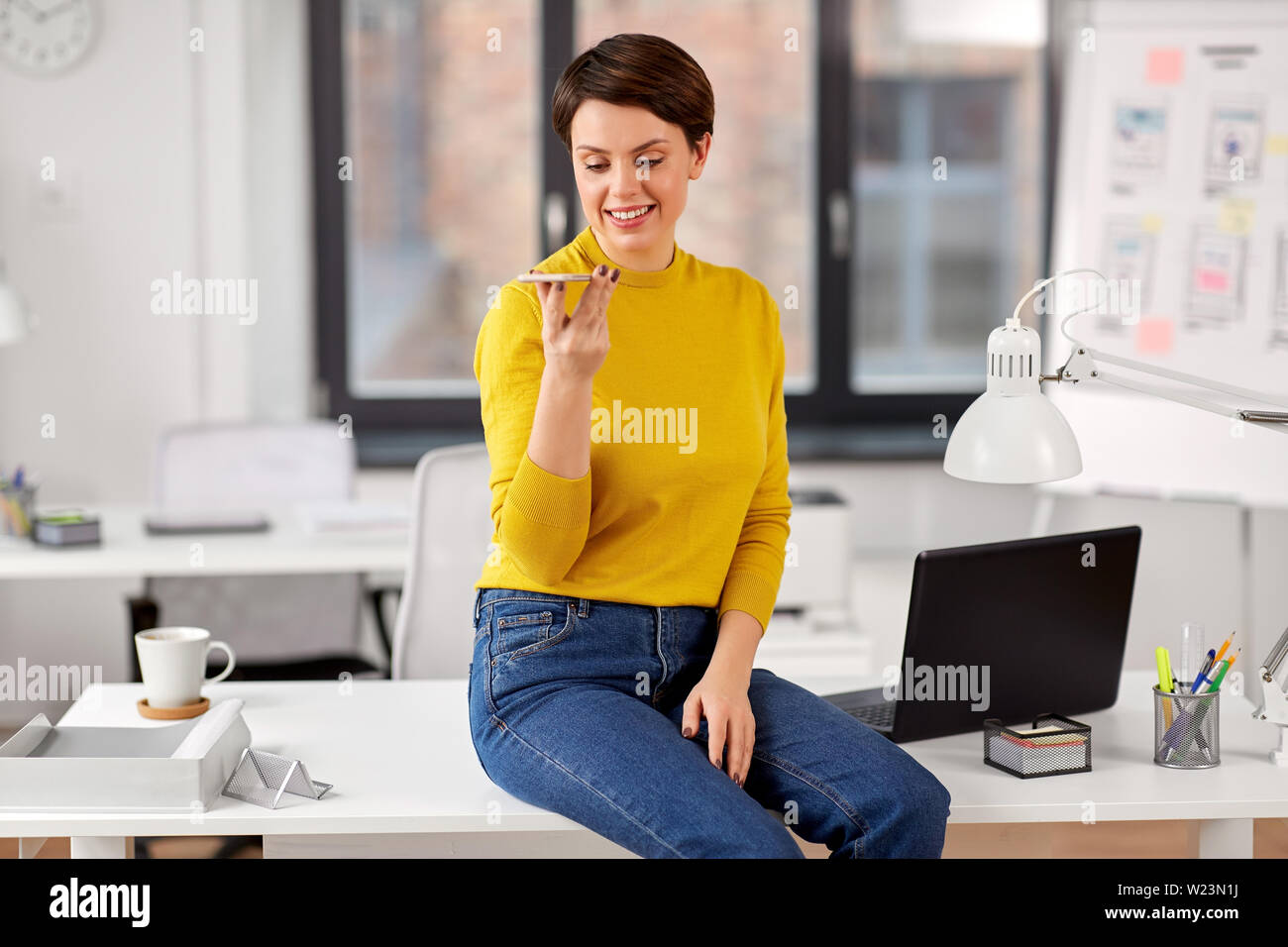 Frau mit Voice-Recorder auf Smartphone im Büro Stockfoto