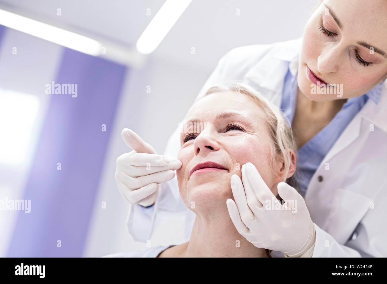 Junge weibliche Arzt prüft das Gesicht des Patienten. Stockfoto