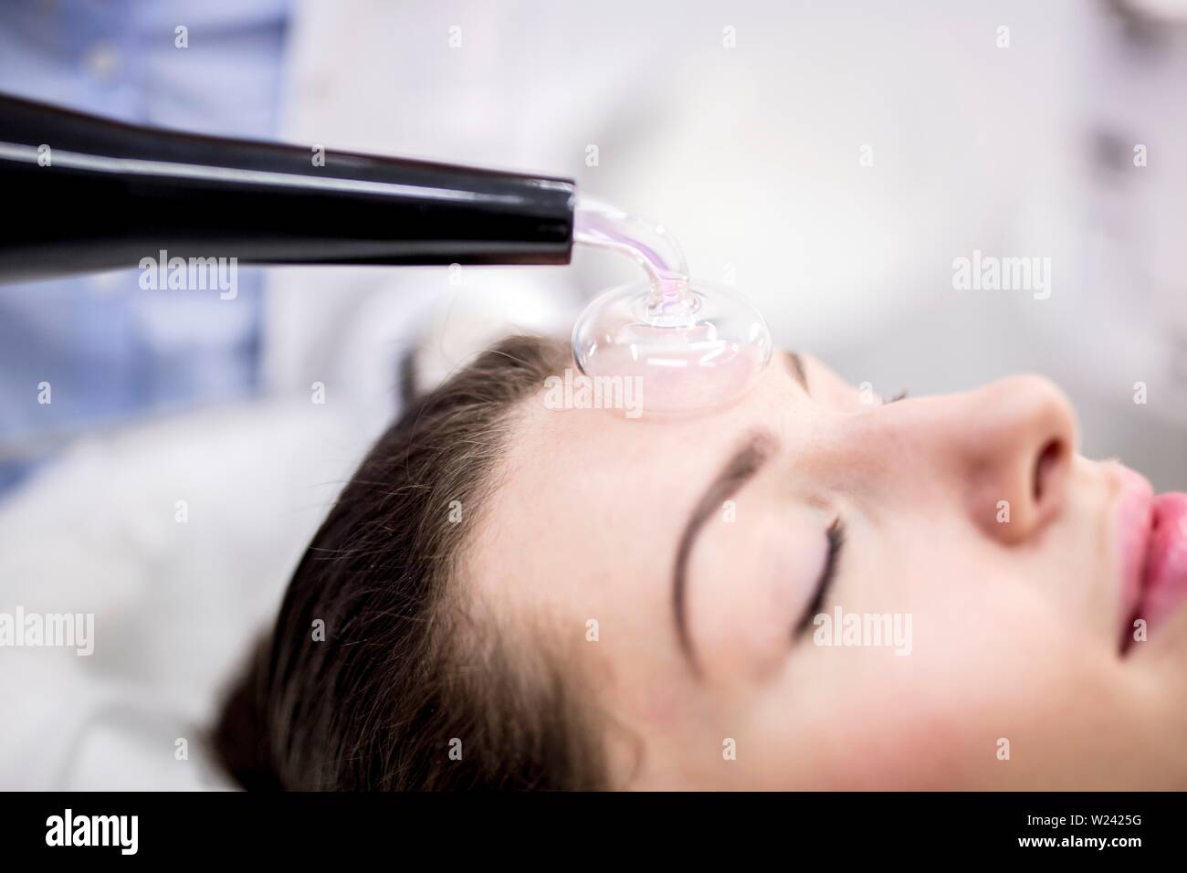 Junge Frauen, die Beauty Behandlung mit einer hohen Frequenz Maschine in einer Klinik. Die hohe Frequenz Maschine verwendet ein Glas pilzförmige Elektrode f Stockfoto