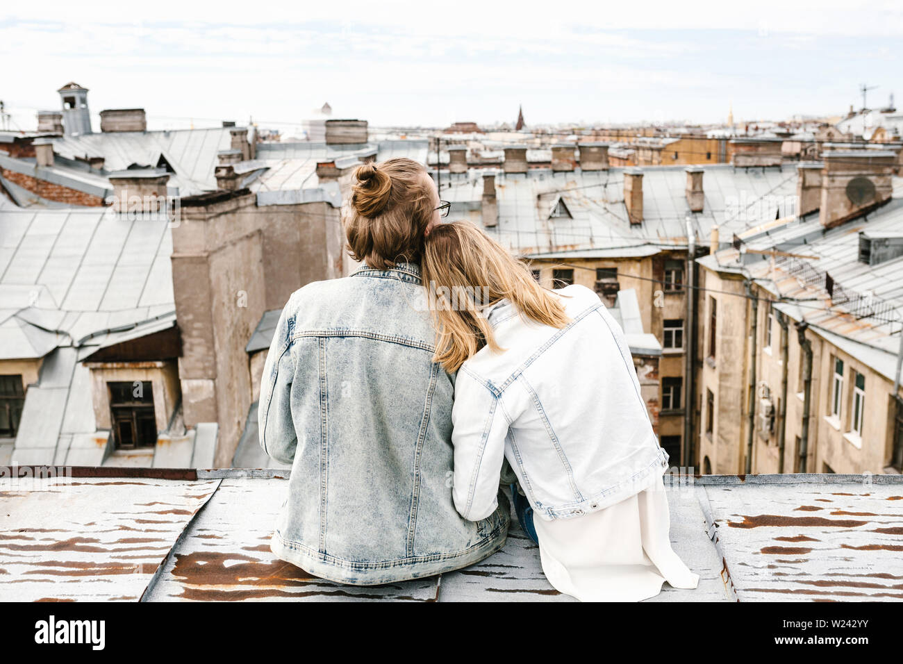 Ein junges Paar sitzt auf dem Dach bewundert und einer schönen Aussicht auf die Stadt. Romantik, Liebe und vertrauensvolle Beziehungen. Oder er Traum oder digital detox zusammen. Stockfoto