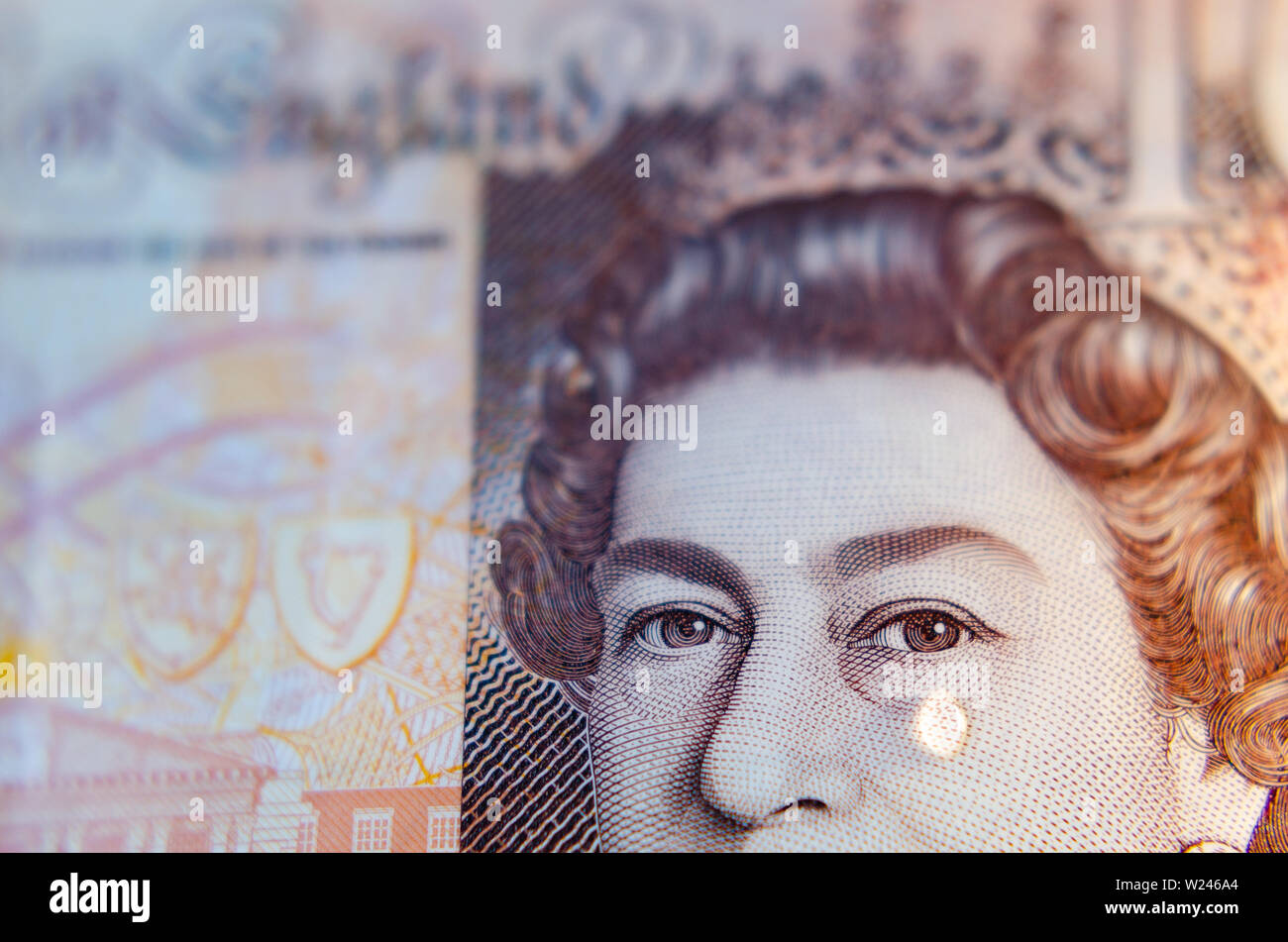 Makrofoto der britischen Pfund-Banknote mit einem Tropfen Wasser als Träne auf dem Gesicht der Königin. Konzeptionelles Foto. Stockfoto