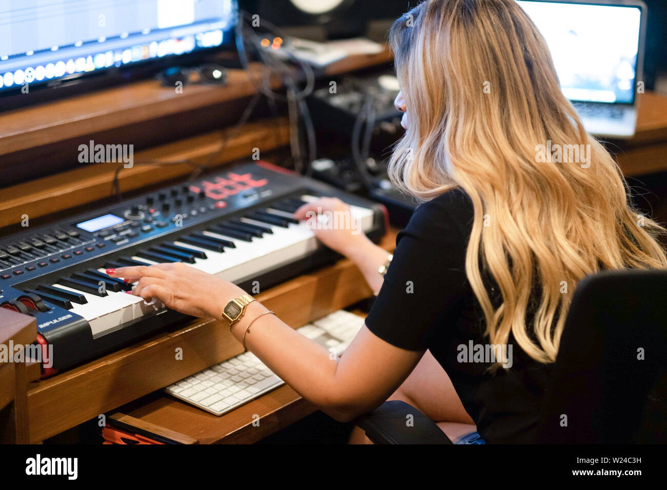 Weibliche Musiker arbeiten in einem modernen Musik Tonstudio. Spielen Sie auf der Tastatur und arbeiten mit einer Musik bearbeiten eine Software auf einem großen Bildschirm Stockfoto