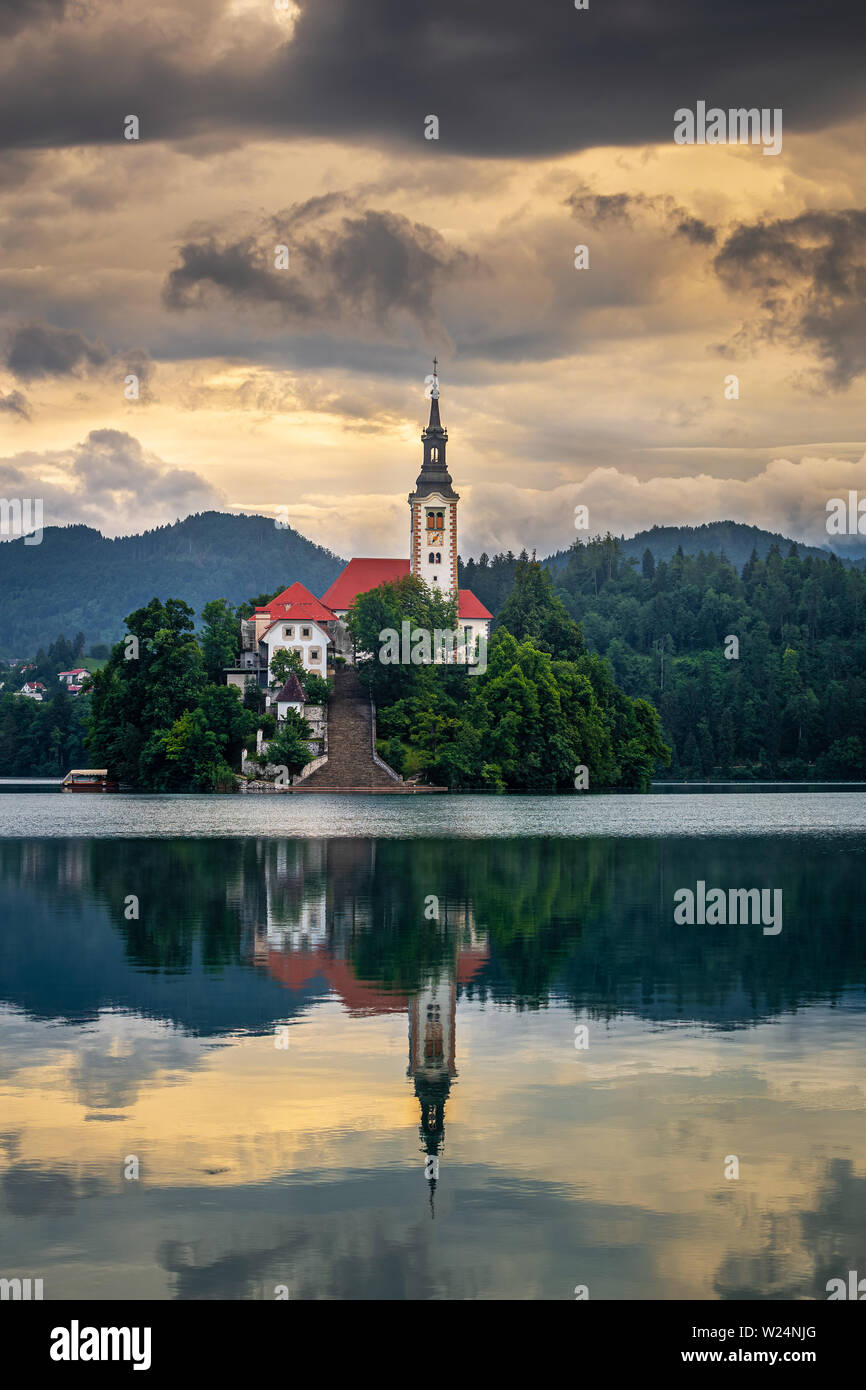 Bled, Slowenien - goldener Sonnenaufgang am See von Bled (Blejsko Jezero) mit der Wallfahrtskirche Mariä Himmelfahrt der Maria auf einer kleinen Insel und von Julischen Alpen Stockfoto