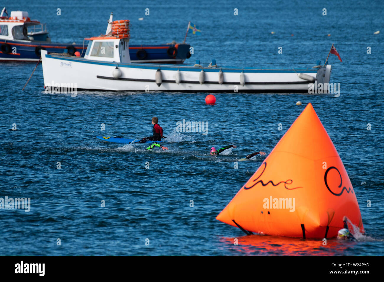 Tenby, Pembrokeshire, West Wales, UK. Vom 5. Juli 2019. Lange Wochenende. Über 10.000 Teilnehmer aus 45 Nationen nehmen an der jährlich stattfindenden Veranstaltung in einer der härtesten Kurse. Rund 35000 Zuschauern sammeln die Schwimmen an diesem Abend zu unterstützen. Die elektrischen Atmosphäre wurde besser durch das herrliche Wetter. Credit: Andrew Bartlett/Alamy leben Nachrichten Stockfoto