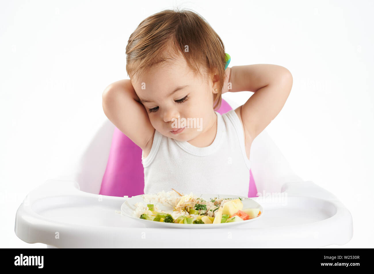 Gelangweilt Baby Mädchen mit Essen auf weiße studio Hintergrund isoliert Stockfoto