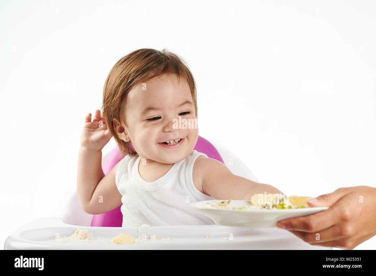 Baby Mädchen spielen mit Essen sitzen auf hohen Stuhl isoliert Stockfoto