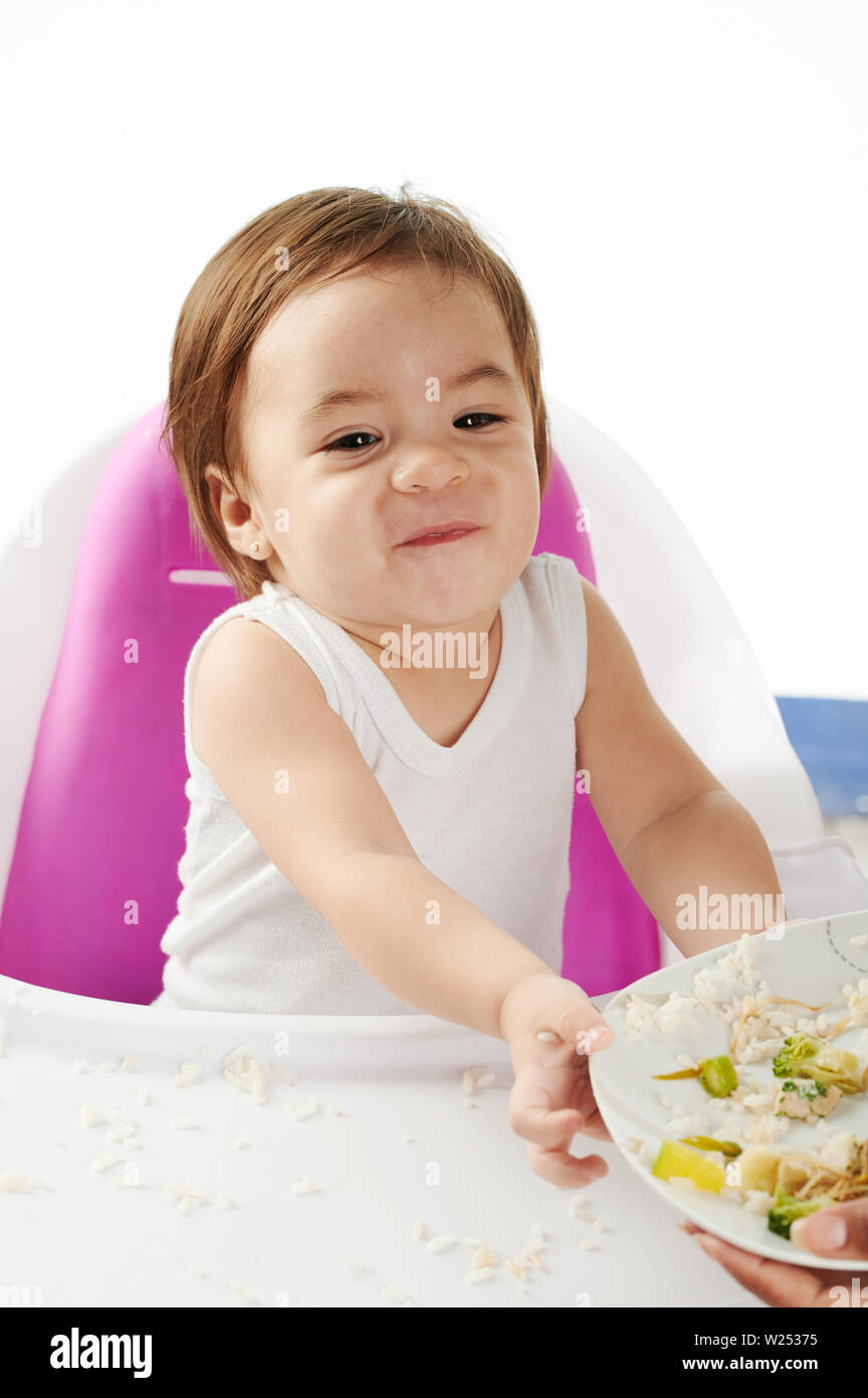 Baby verweigern Essen auf dem Teller sitzen Hochstuhl isoliert Stockfoto