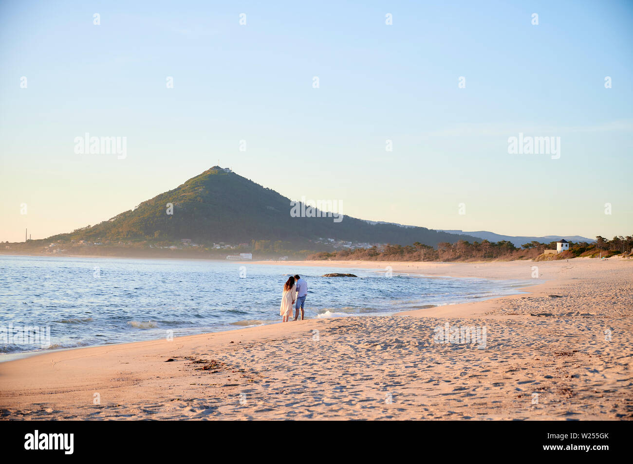 Frau in einem weißen Kleid am Strand Moledo, Portugal. Mit einem Berg im Hintergrund Stockfoto
