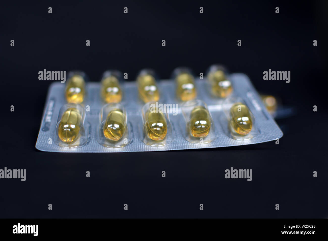 Blisterpackung mit gelben Pillen fille mit flüssigen Medikamenten auf Schwarz studio Hintergrund Stockfoto