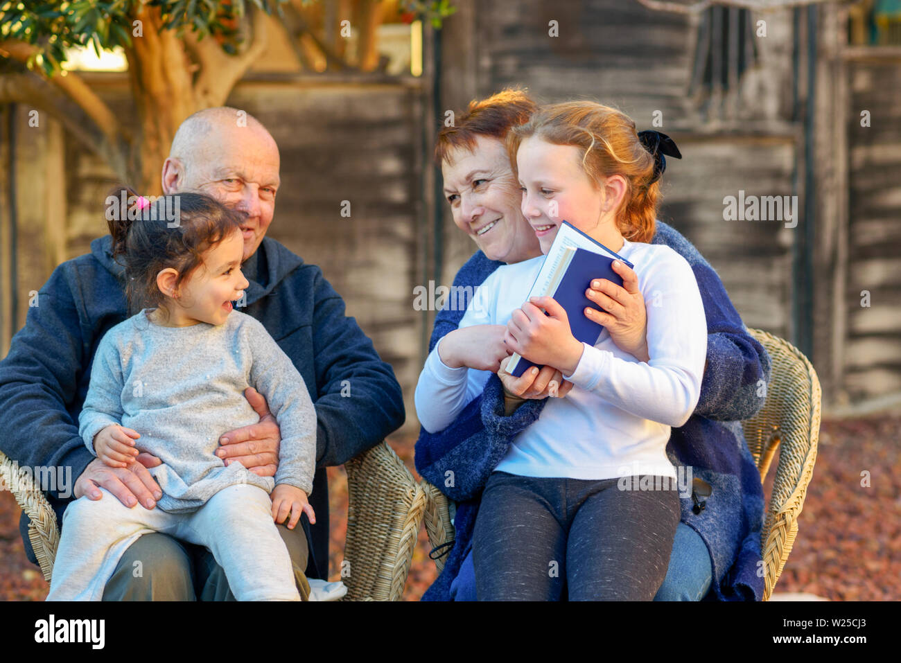 Schönes glückliches Ehepaar und Enkelinnen ein Buch lesen gemeinsam in der Natur im Sommer. Stockfoto
